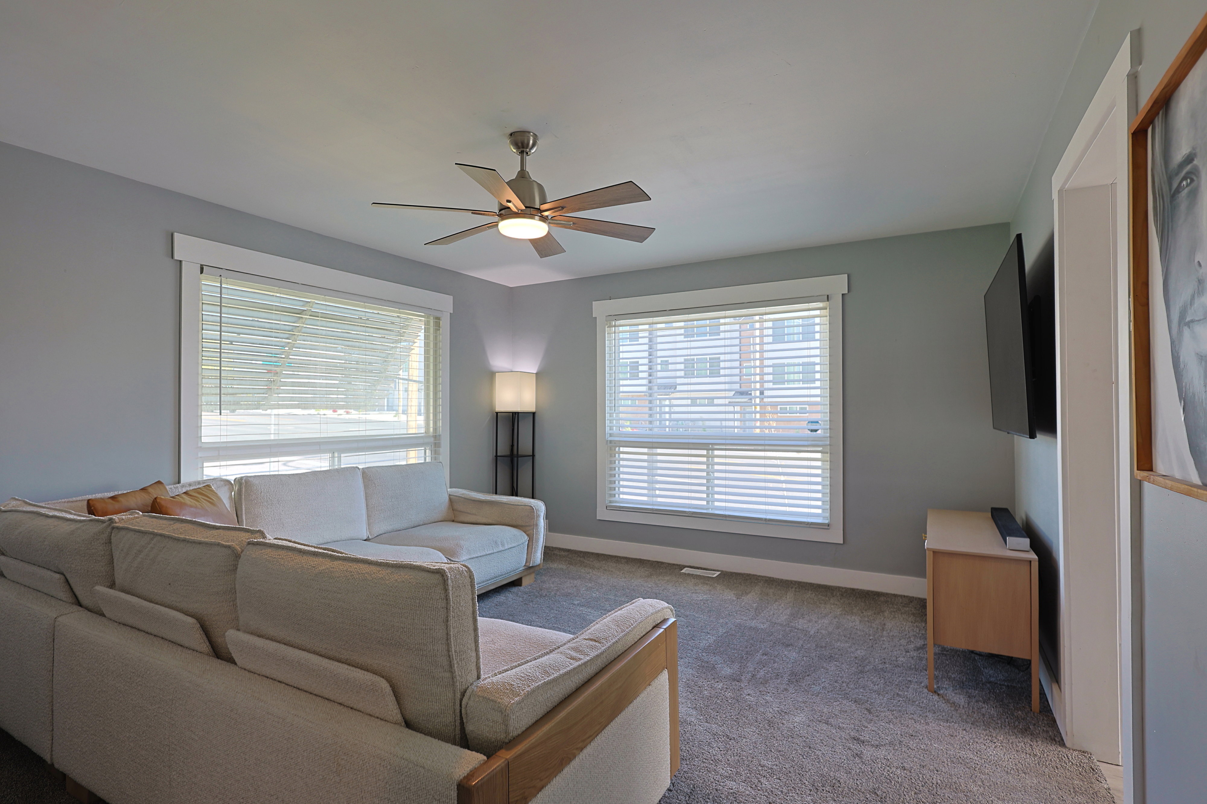 Spacious living area featuring neutral-toned walls and plush grey carpeting