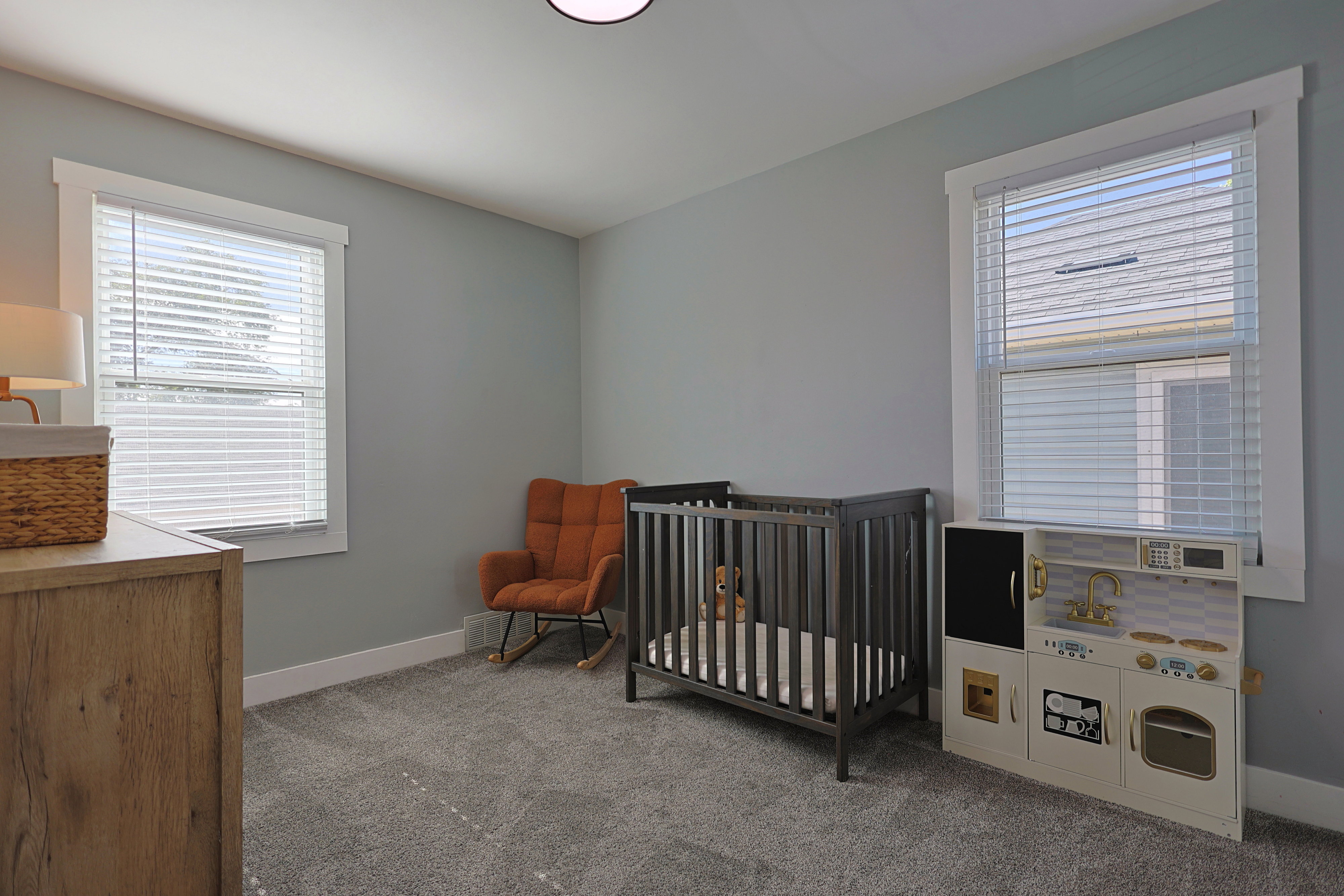 Room featuring soft gray wall paint, two windows with white blinds, white trim, and gray carpet flooring