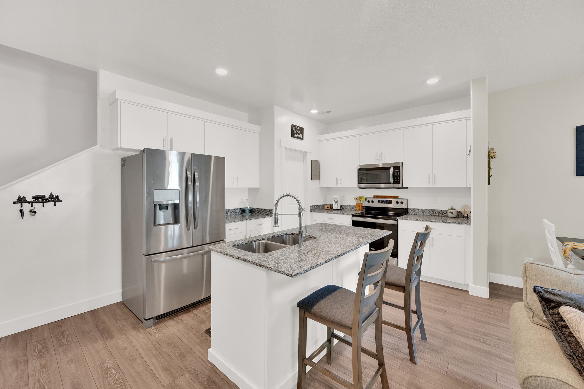 Kitchen with white cabinetry, stainless steel appliances, granite countertops, and a central island with a double basin sink
