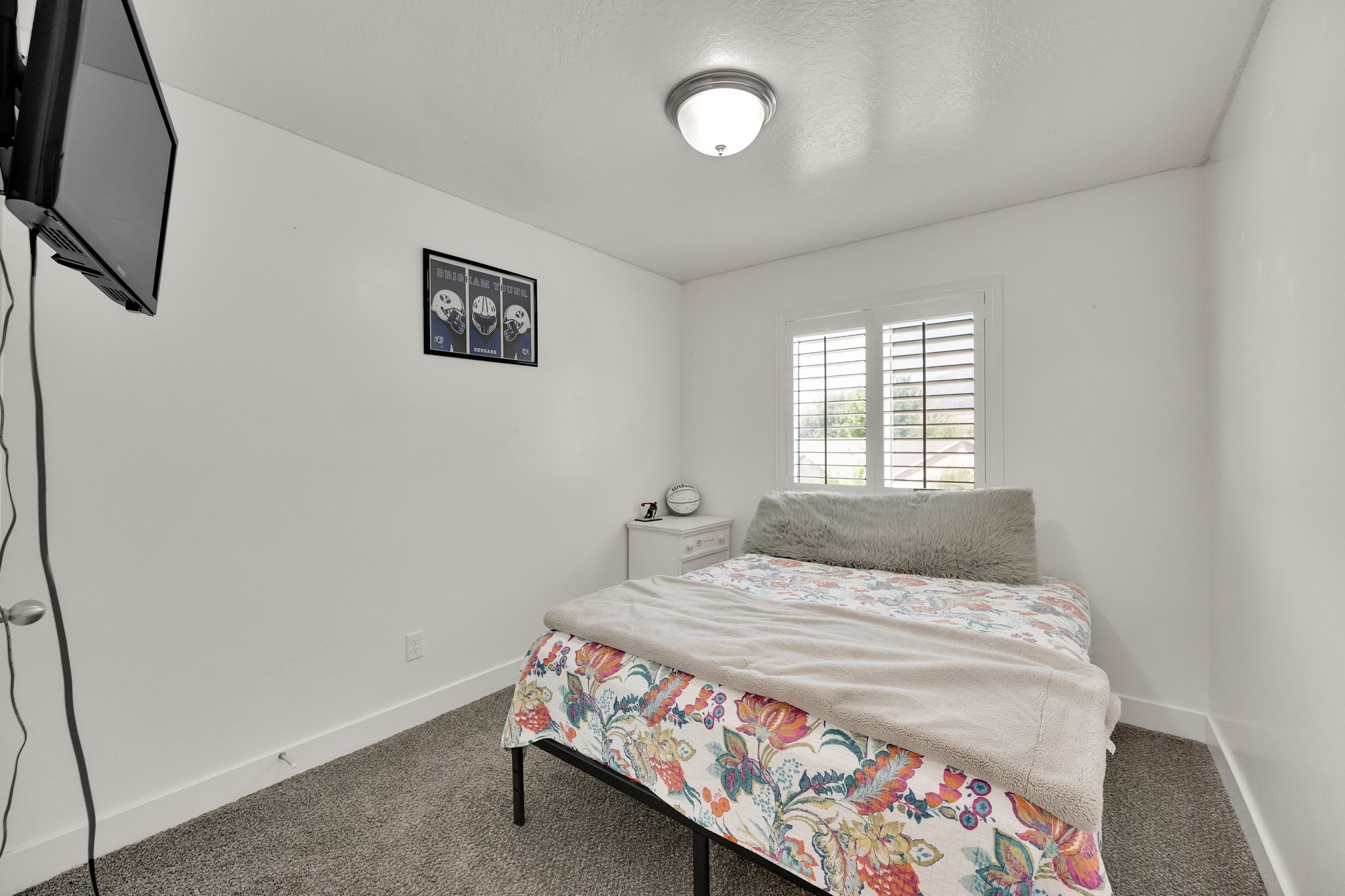 Room featuring neutral wall paint, carpet flooring, a window with plantation shutters, white baseboards, and a semi-flush mount ceiling light fixture