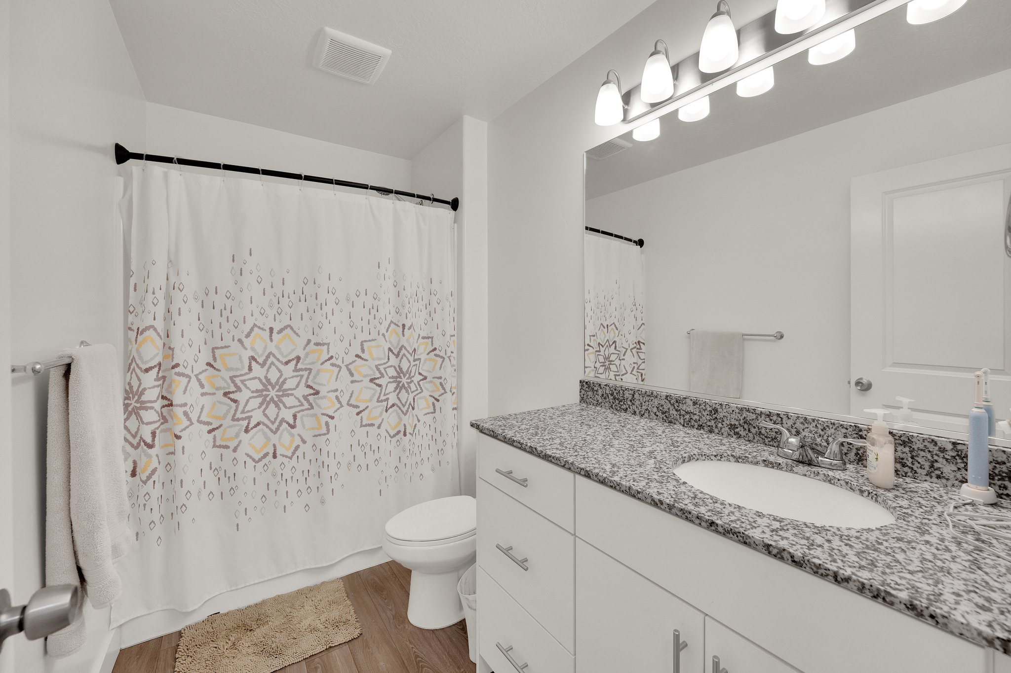 Bathroom featuring a white vanity with a speckled countertop, undermount sink, and chrome fixtures