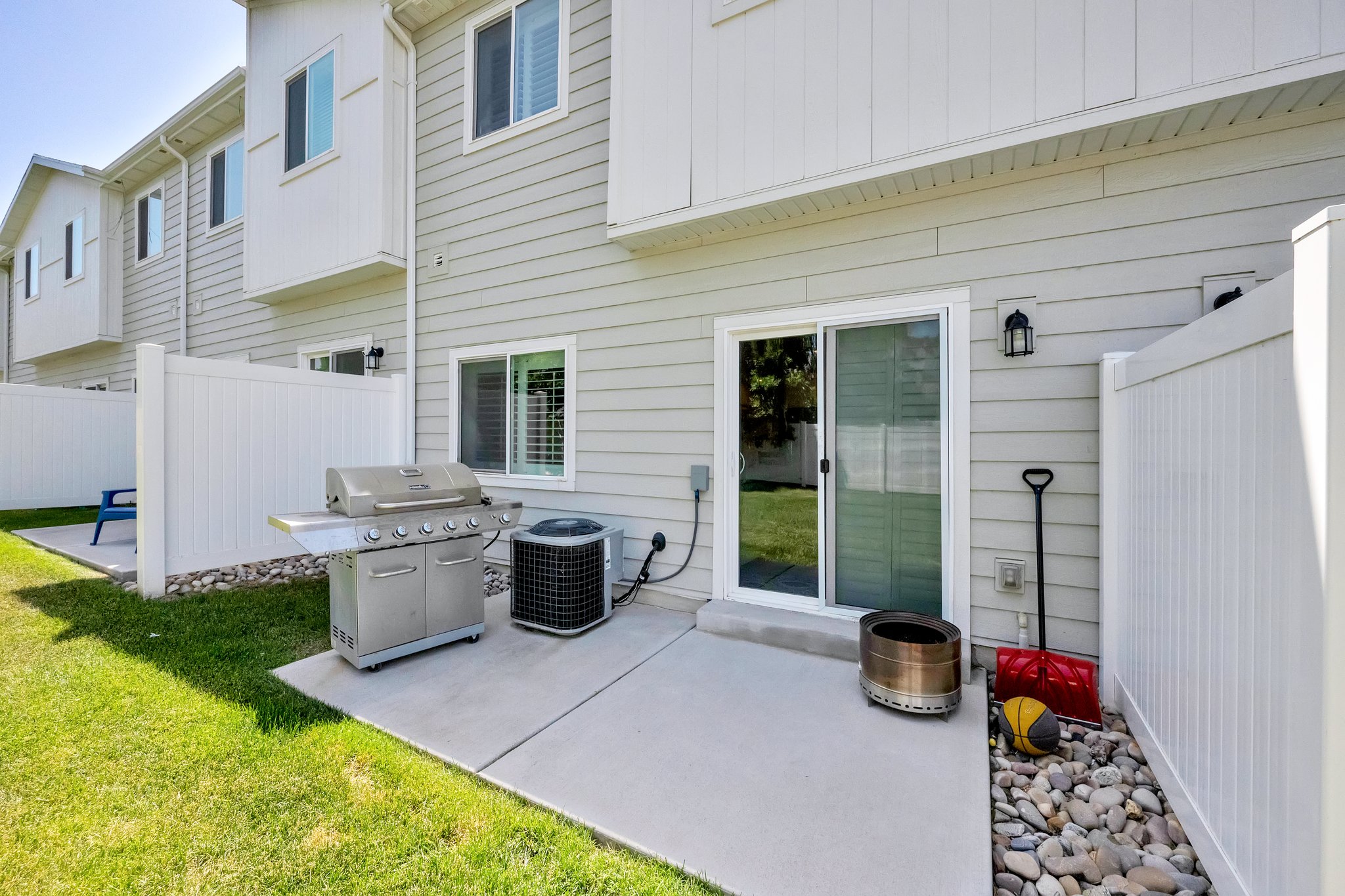 Private patio area featuring a sliding glass door entry, exterior wall lantern, and a stone-filled border