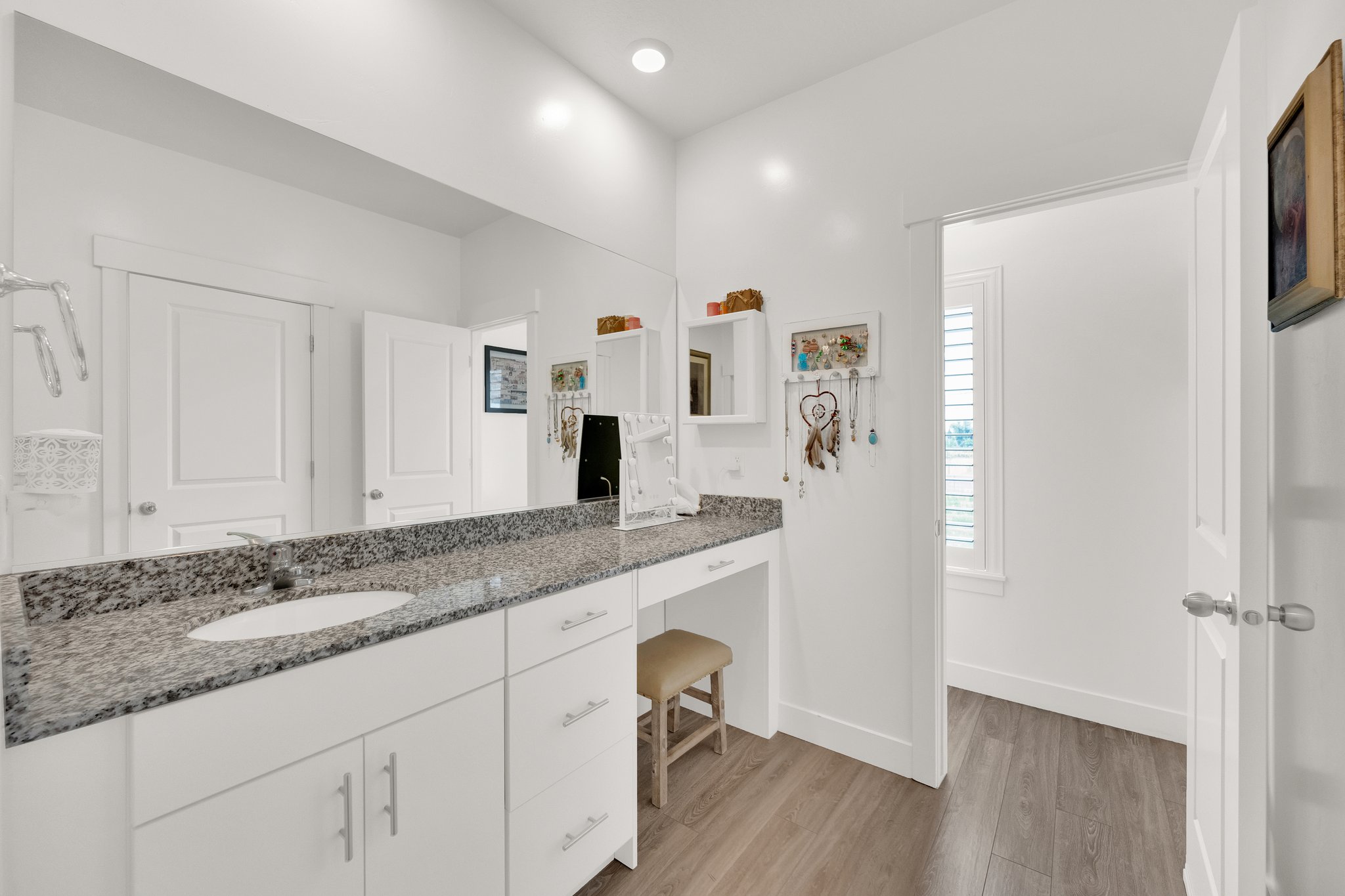 Modern vanity featuring a granite-style countertop, integrated single sink, and white cabinetry with brushed nickel hardware