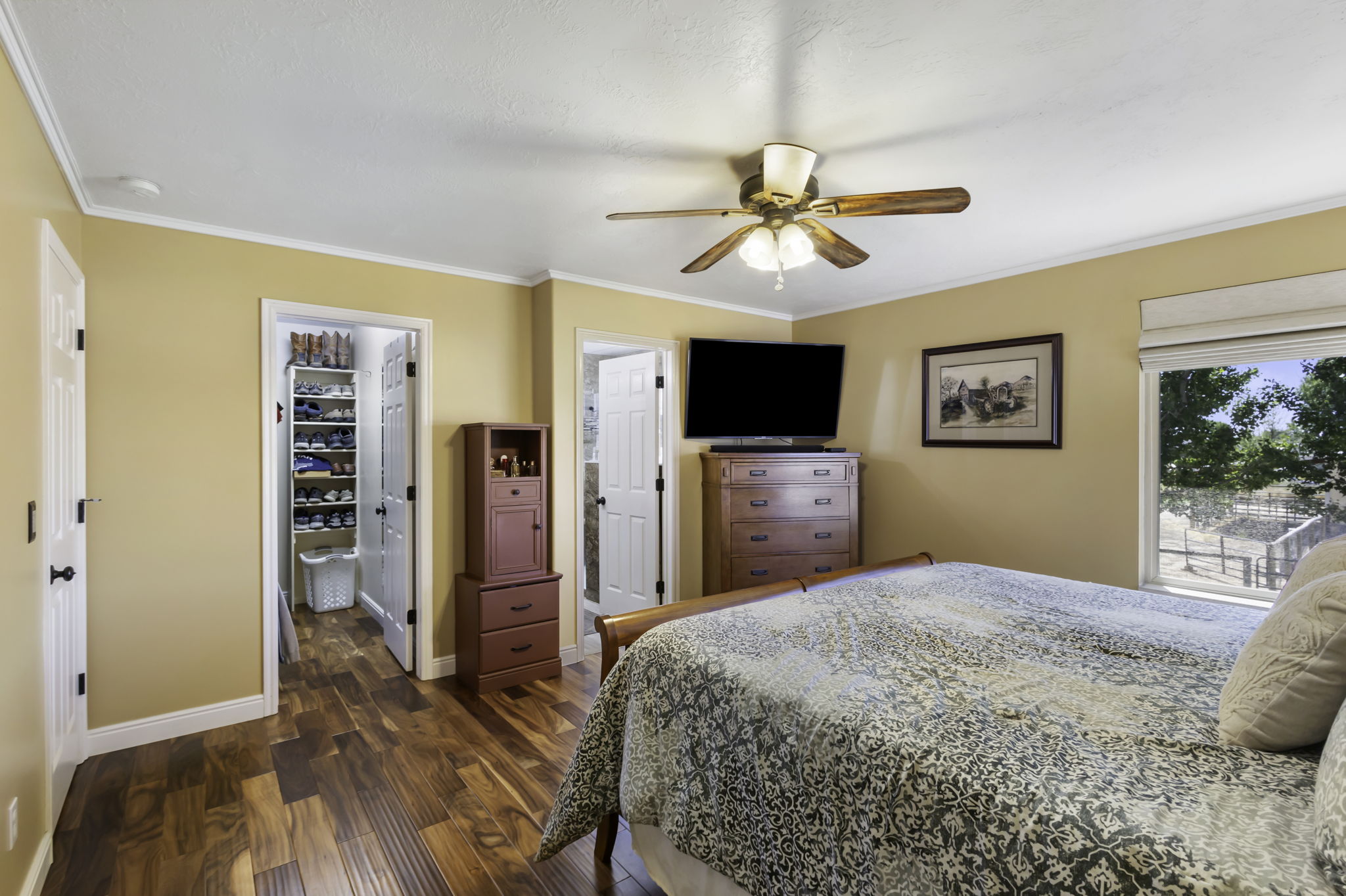 Spacious room featuring wood-finish flooring, a ceiling fan, and a large window