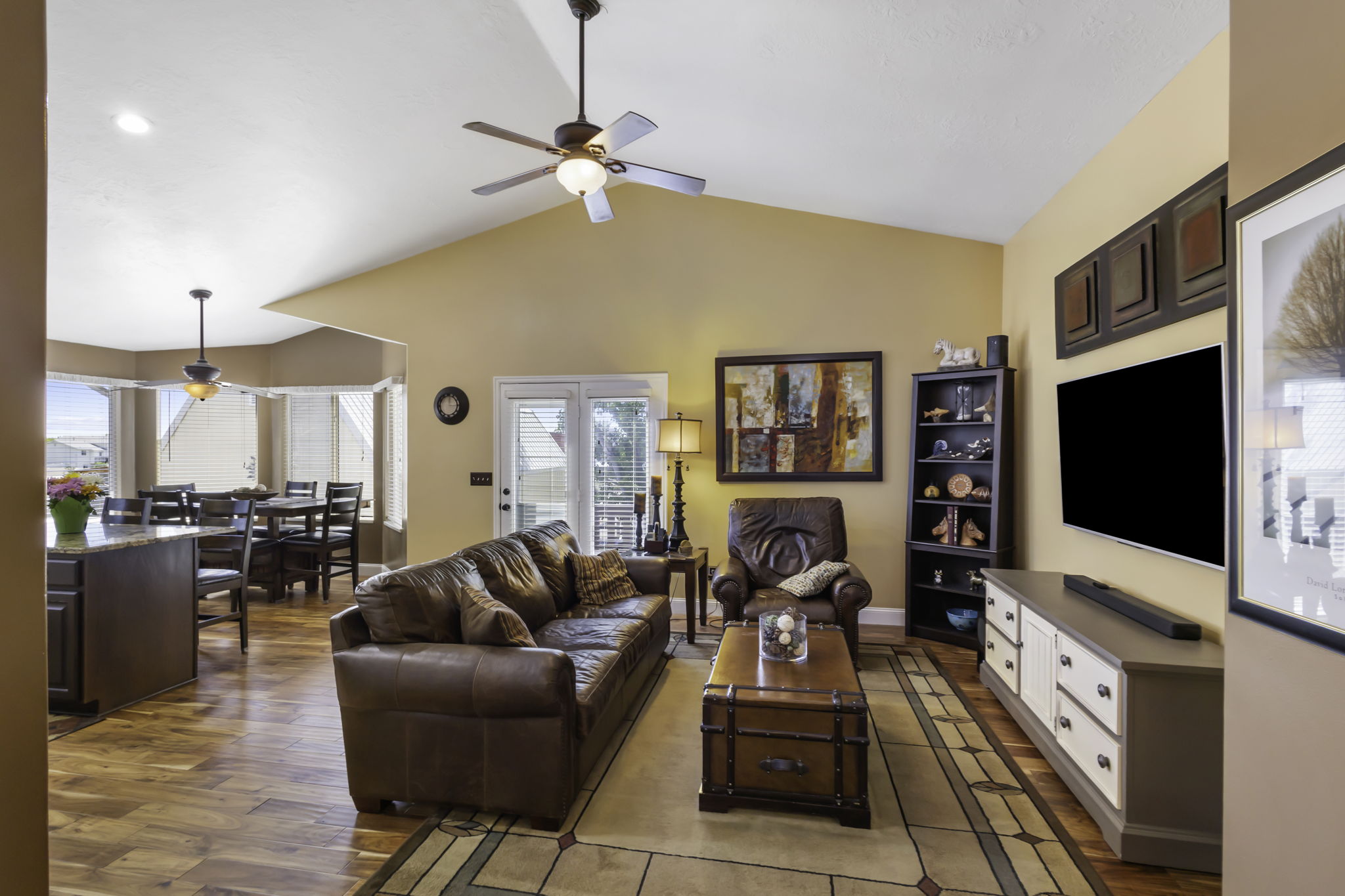 Living area with vaulted ceiling, hardwood flooring, and recessed lighting