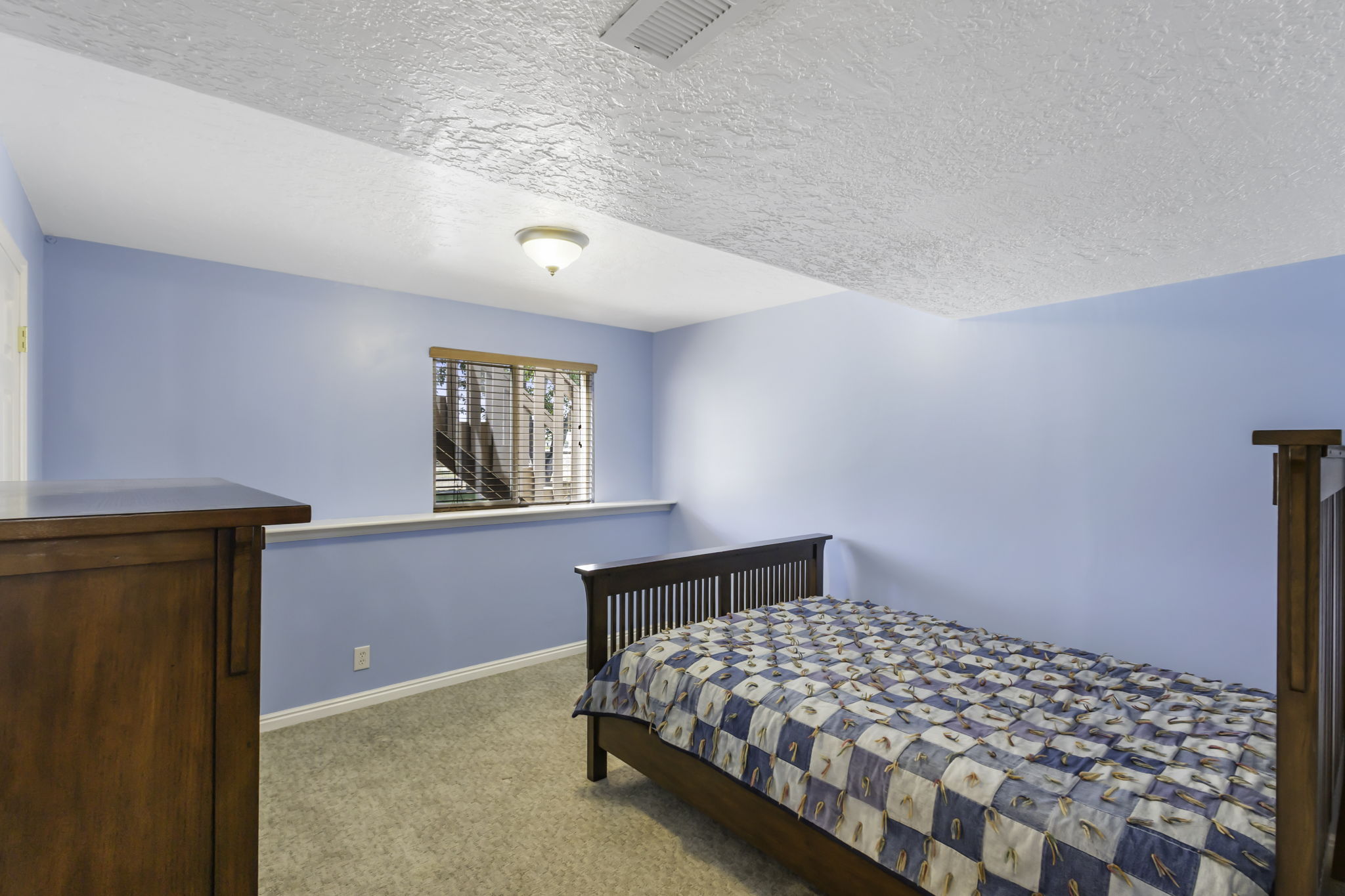 Inviting room featuring blue walls, light-colored carpet flooring, a window with wood blinds, and a built-in shelf