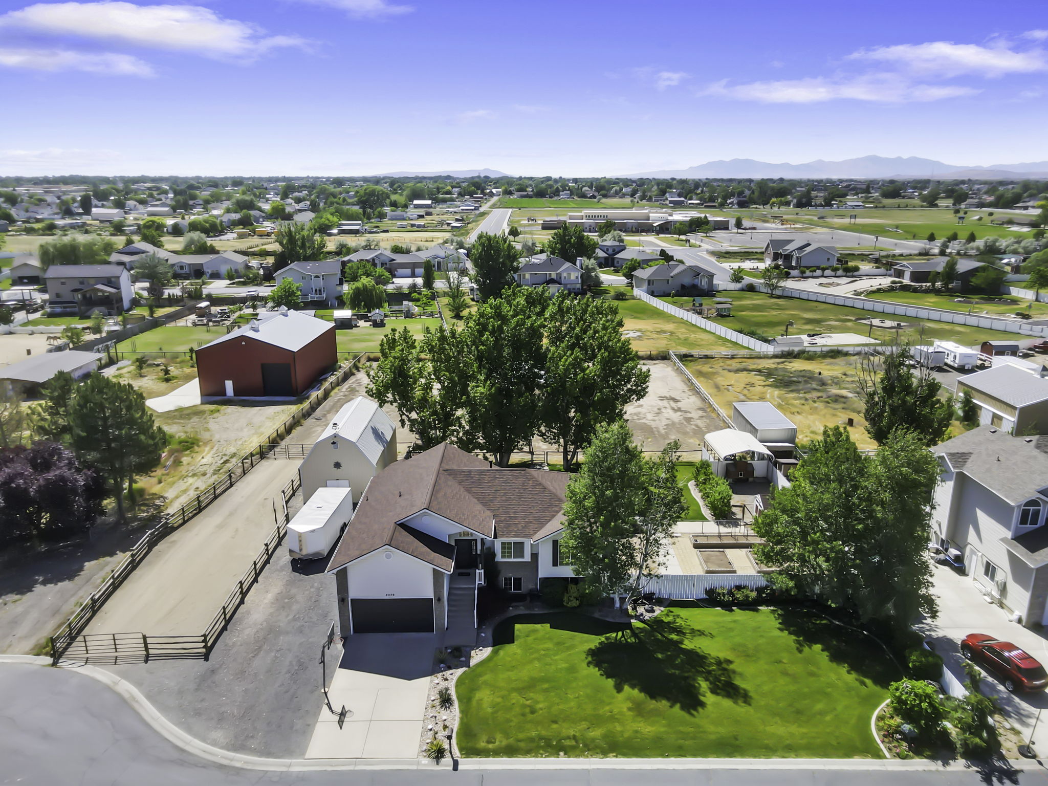 Aerial perspective, featuring a manicured front lawn,  paved driveway, expansive RV parking complete with a two-car garage