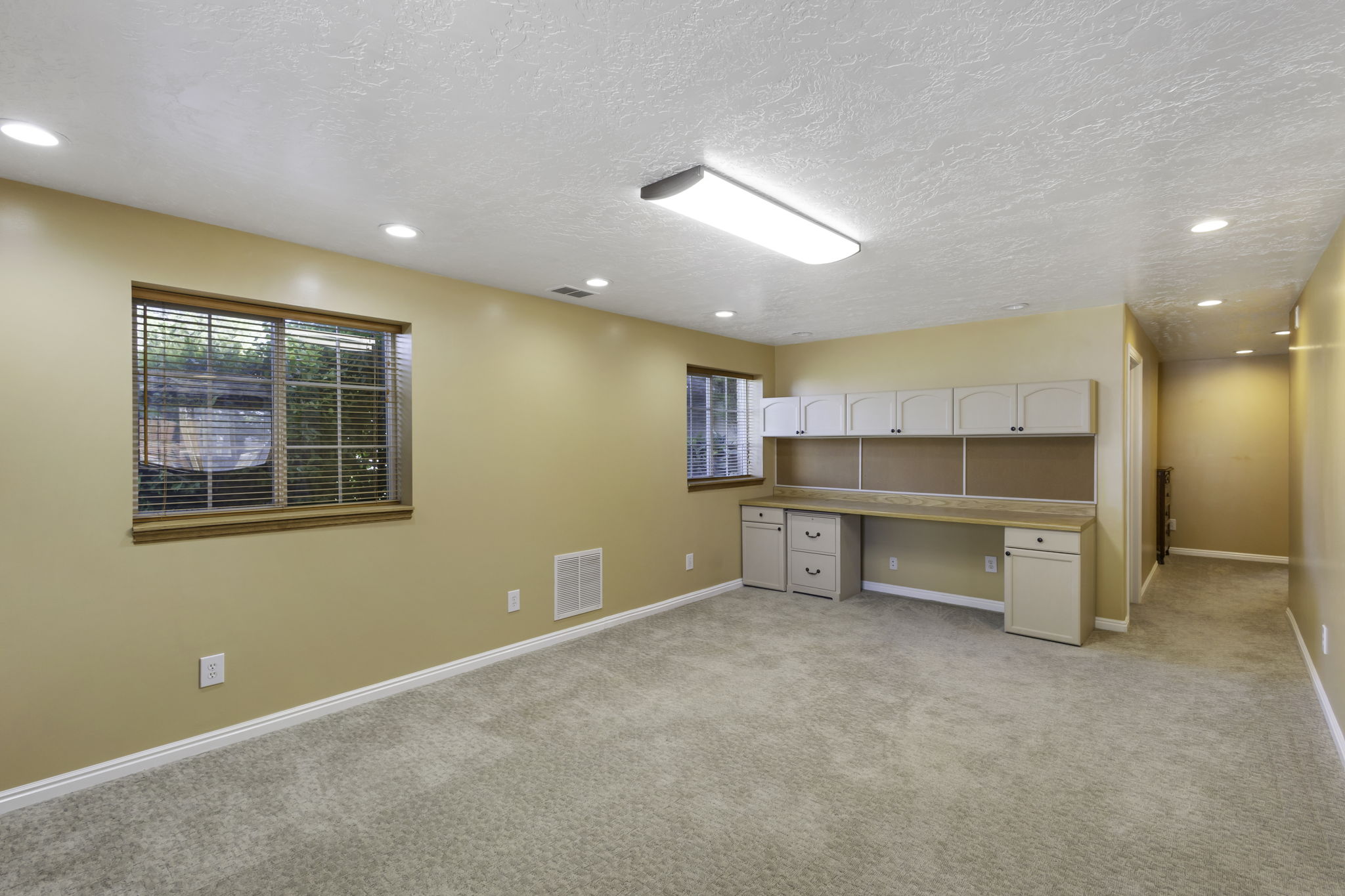 Built-in desk with overhead cabinetry, recessed lighting, window with wood blinds, and carpeted flooring