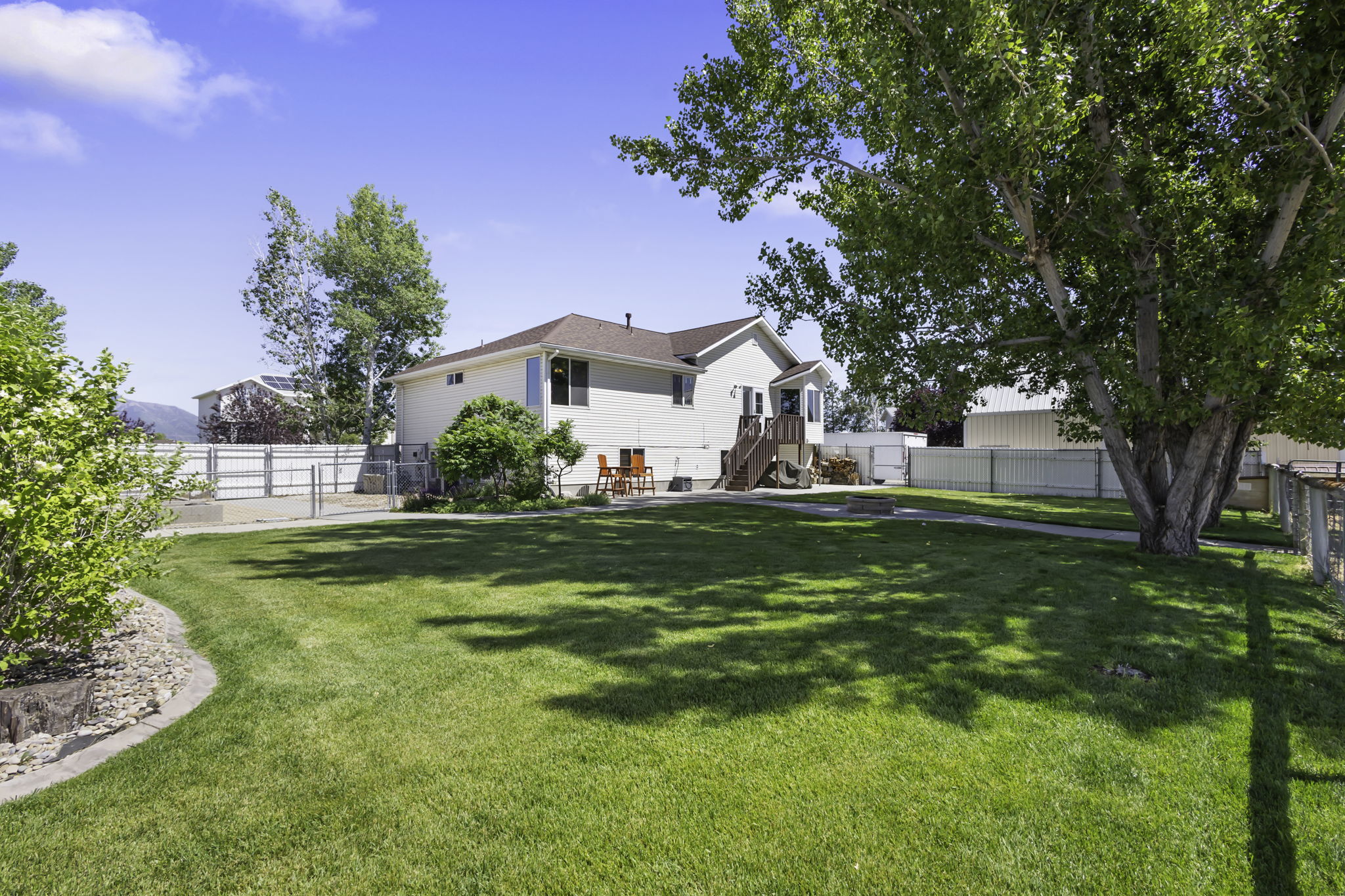 Expansive green lawn with mature trees providing natural shade