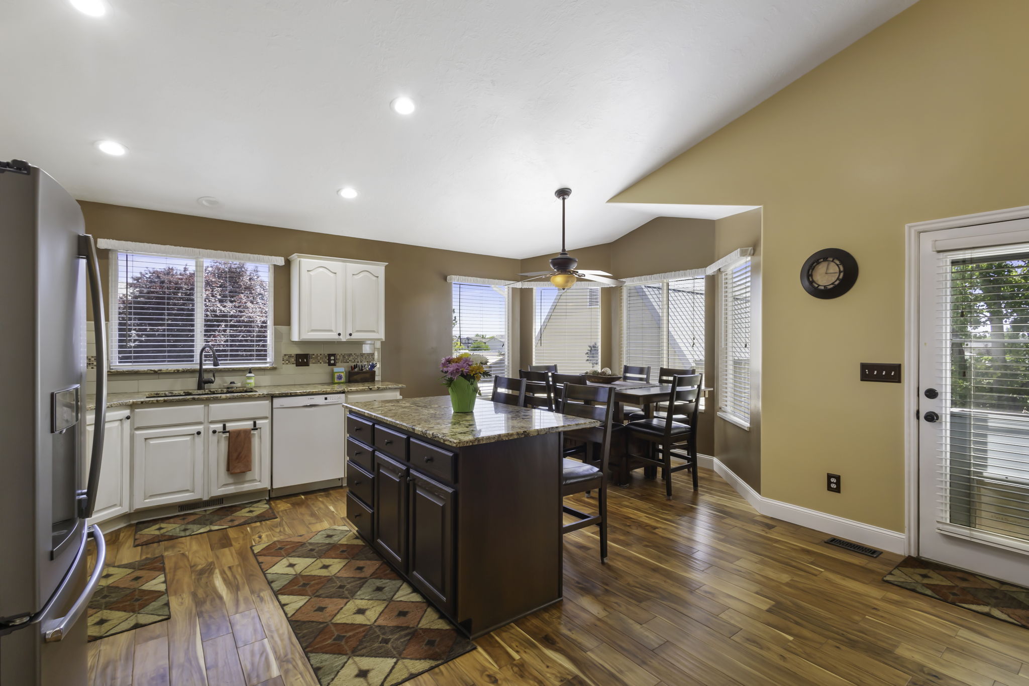 Kitchen featuring rich wood-finish flooring, white cabinetry, and granite countertops