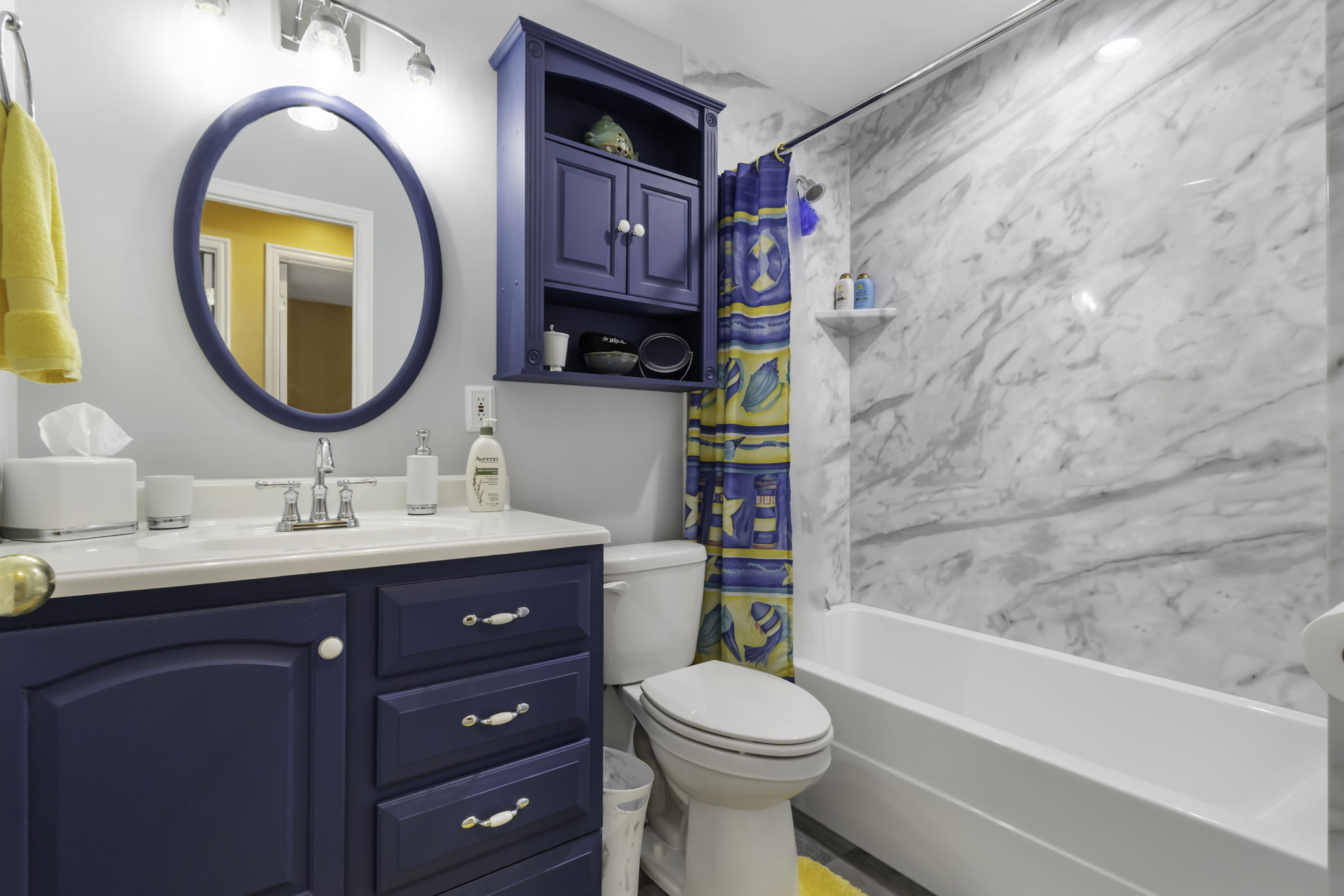 White vanity countertop with an undermount sink, a blue oval mirror, and a coordinating blue vanity cabinet