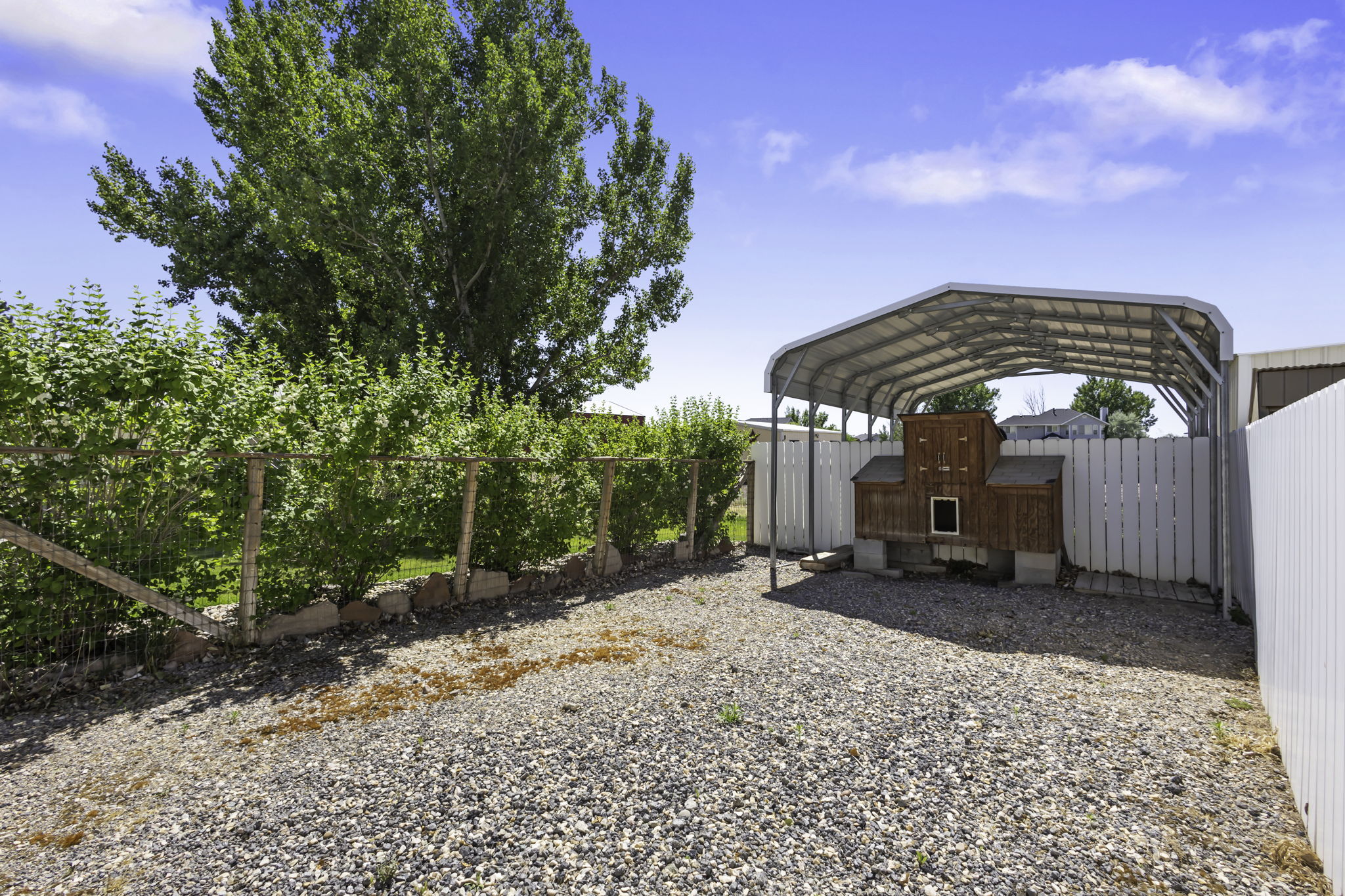 Gravel yard area featuring a  covered dog penthouse and run.