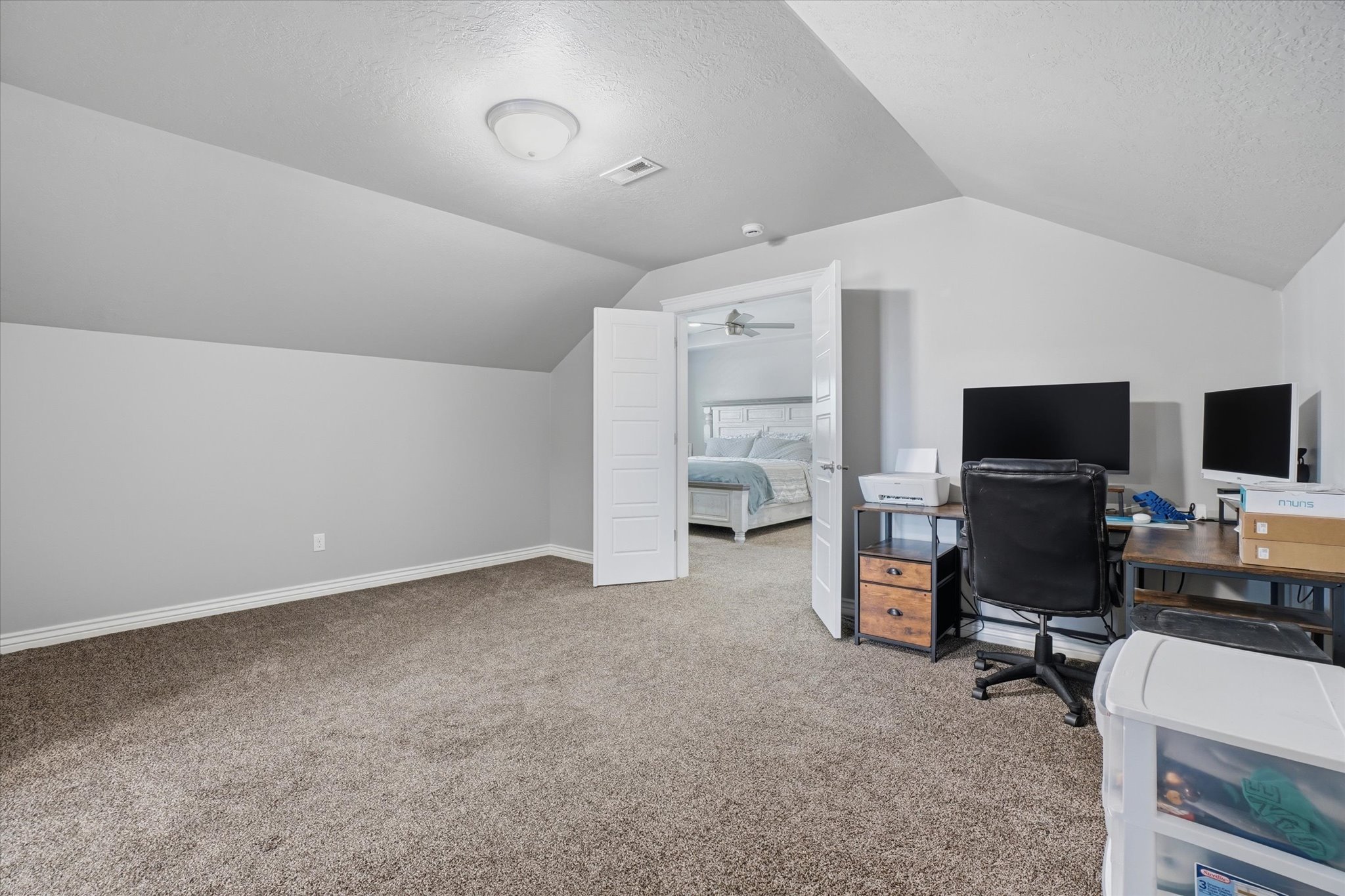 Carpeted room featuring a sloped ceiling and light gray walls