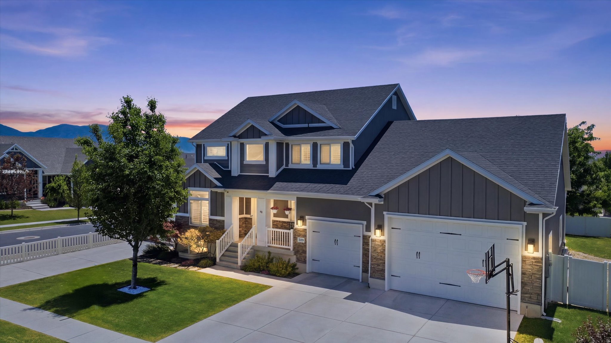Contemporary two-story residence featuring a dark gray exterior, white trim, and stone accents