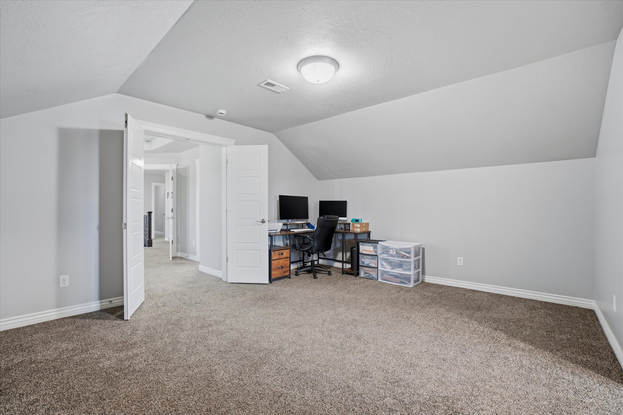 Carpeted room with sloped ceilings and light grey wall paint