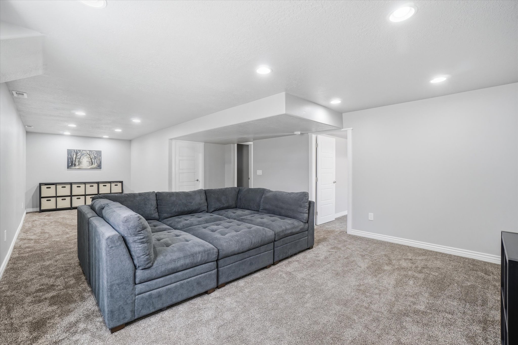 Spacious room with gray textured carpeting and light gray wall paint
