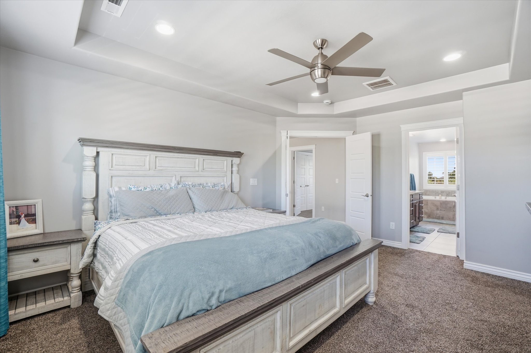 Tray ceiling with recessed lighting and a brushed nickel ceiling fan