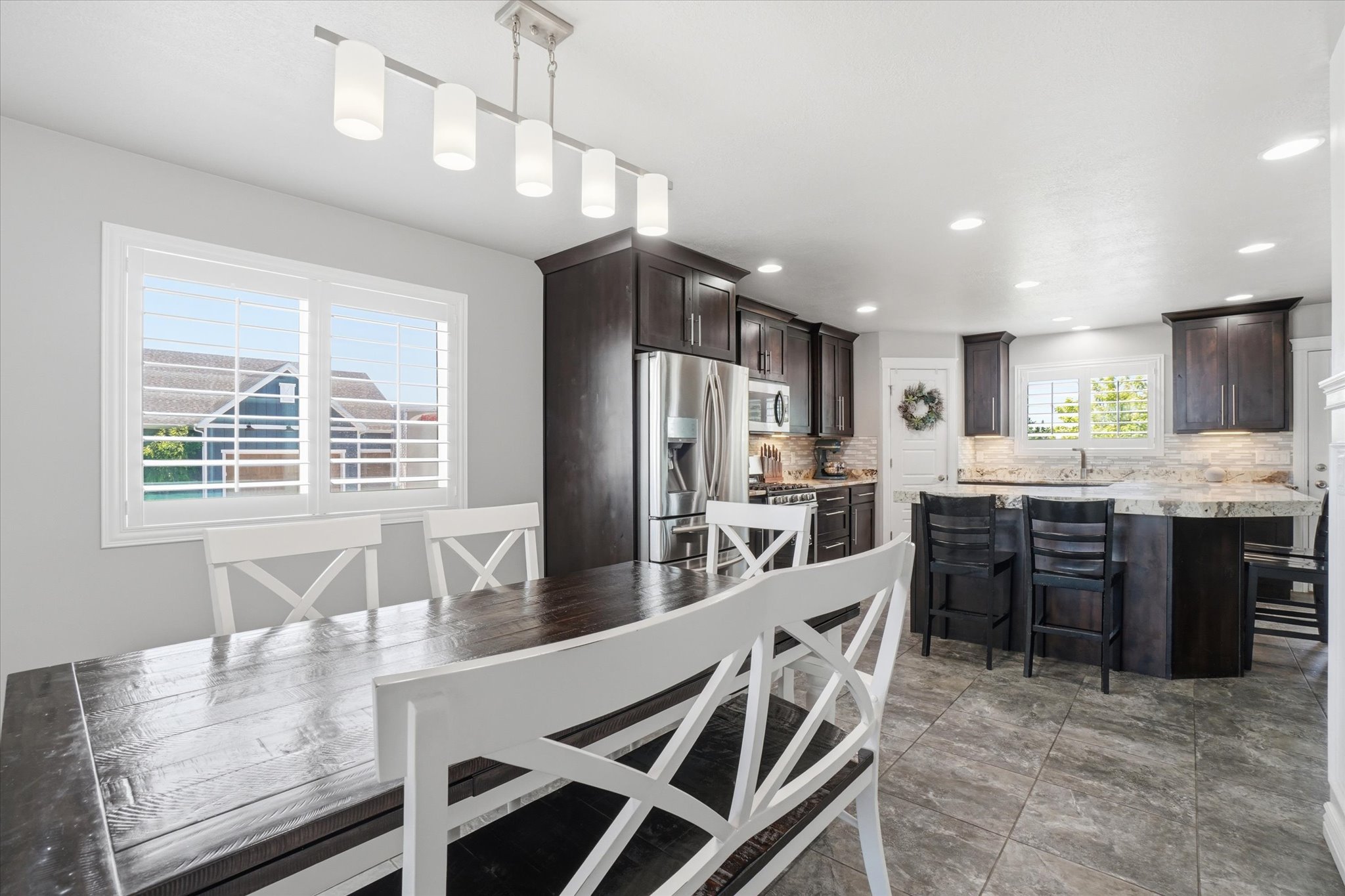 Open-concept kitchen and dining area featuring dark wood-finish cabinetry, stainless steel appliances, and a stone-finish countertop