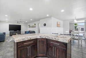 Kitchen island featuring dark wood cabinetry and a multi-toned stone countertop