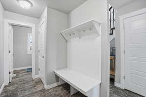 Built-in white bench with coat hooks and beadboard backing, set against light gray walls