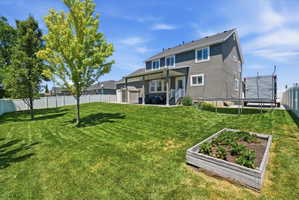 Spacious backyard featuring an expansive lawn, mature trees, and a raised garden bed