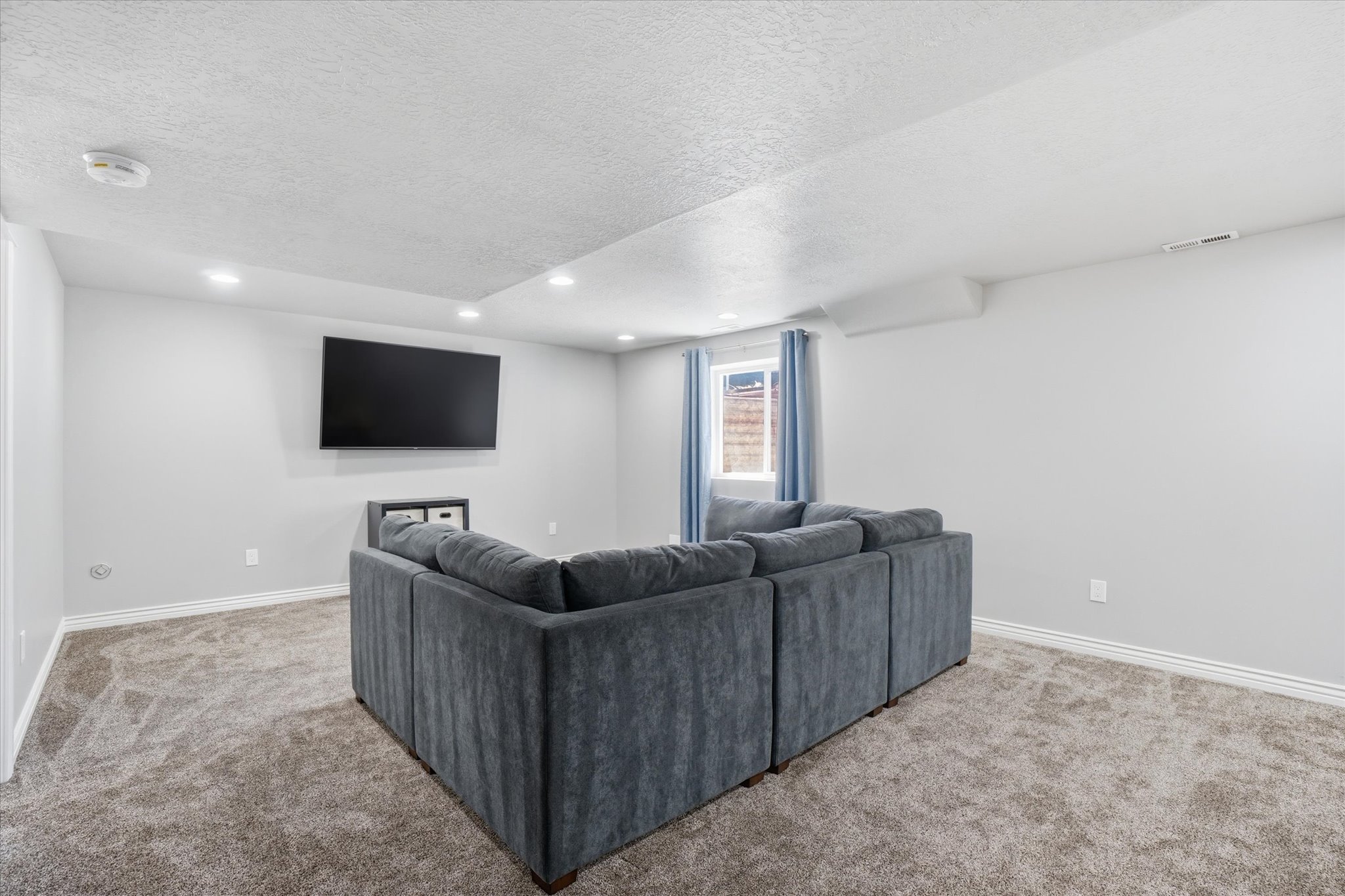 Spacious room featuring light gray walls, recessed lighting, and soft carpet flooring