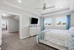 Spacious bedroom featuring neutral wall paint, plush carpeting, and a tray ceiling with recessed lighting