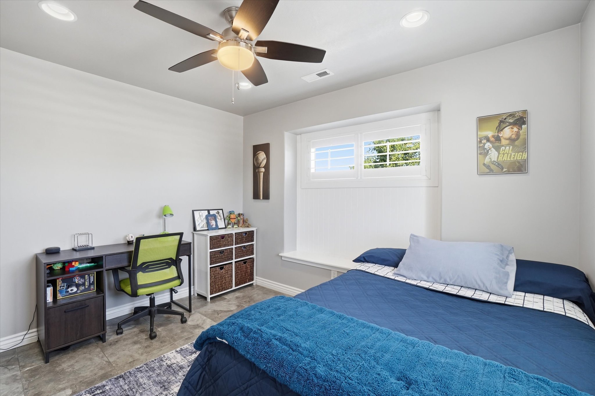 Bedroom featuring a built-in window bench, white window shutters, and a ceiling fan with integrated lighting