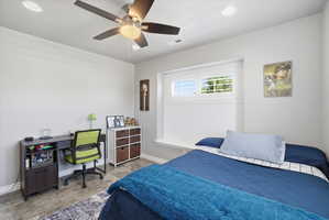 Bedroom featuring a built-in window bench, white window shutters, and a ceiling fan with integrated lighting