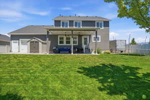 Expansive green lawn with a covered patio featuring recessed lighting and a ceiling fan
