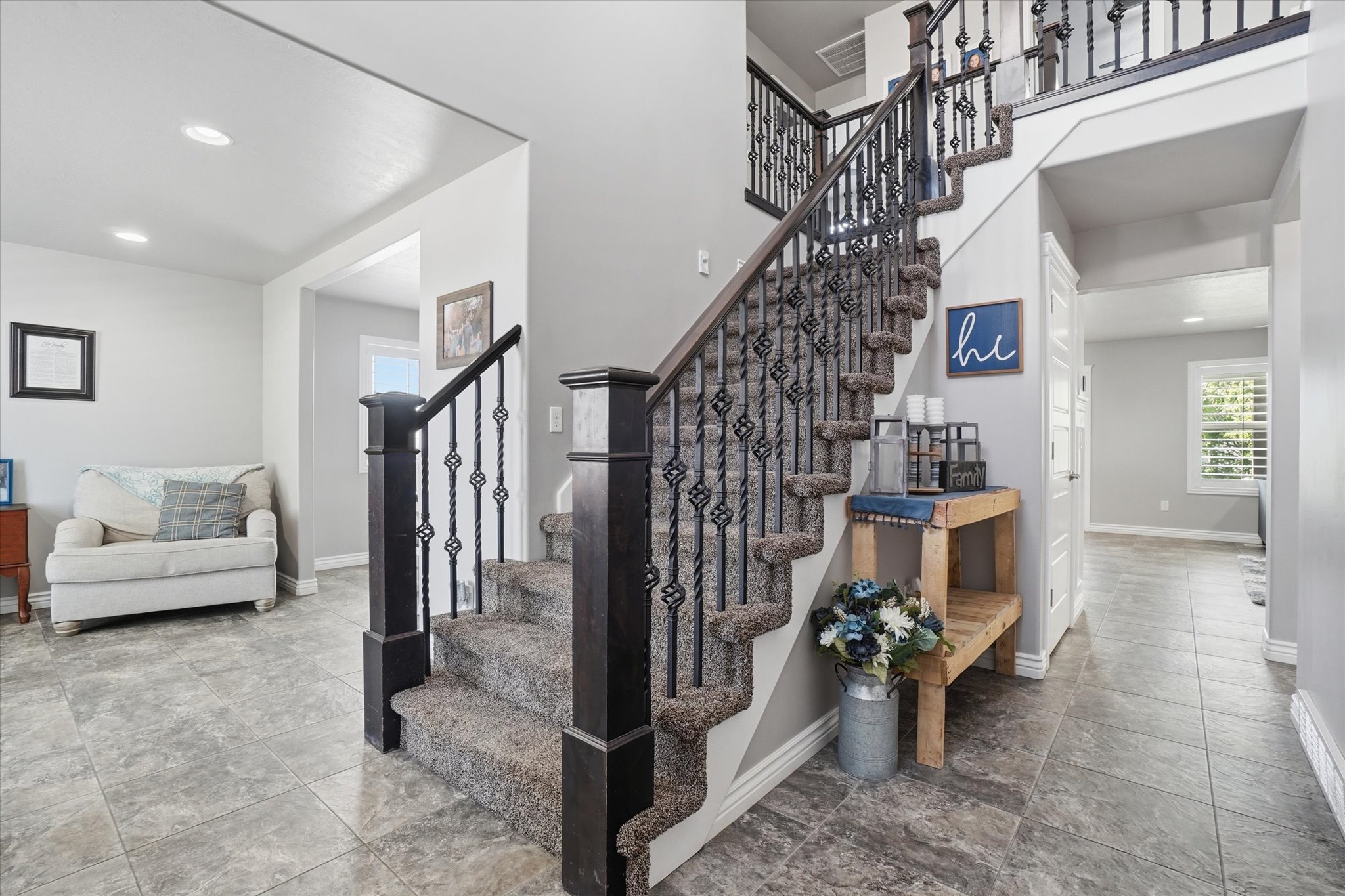 Grand staircase featuring dark wood newel posts and ornate wrought iron balusters