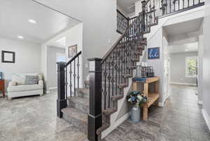 Grand staircase featuring dark wood newel posts and ornate wrought iron balusters