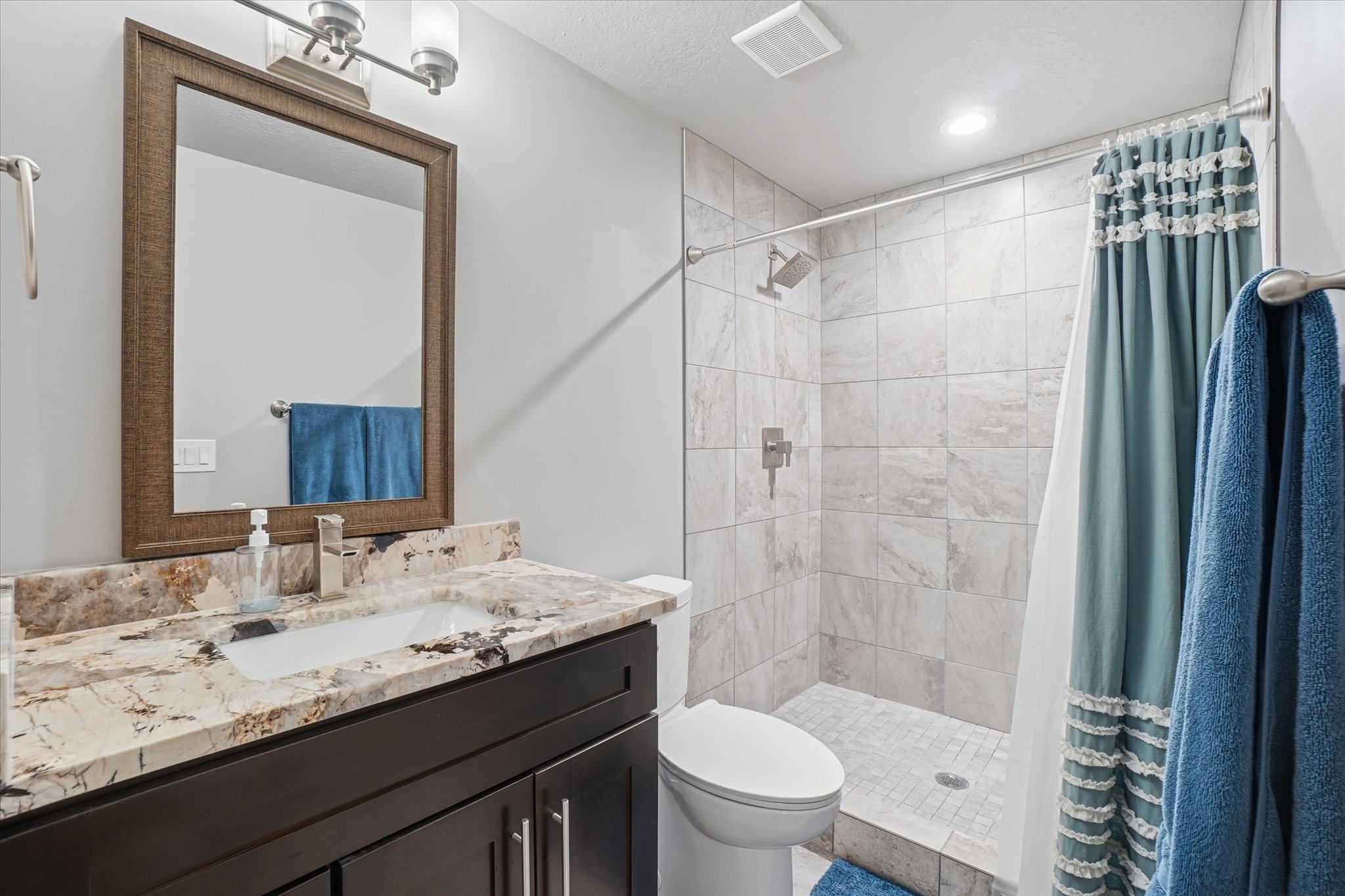 Bathroom featuring a dark wood vanity with a stone countertop, an undermount sink, and a brushed nickel faucet