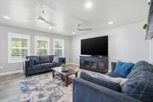 Expansive living area featuring three large windows with plantation shutters, recessed lighting, and two ceiling fans