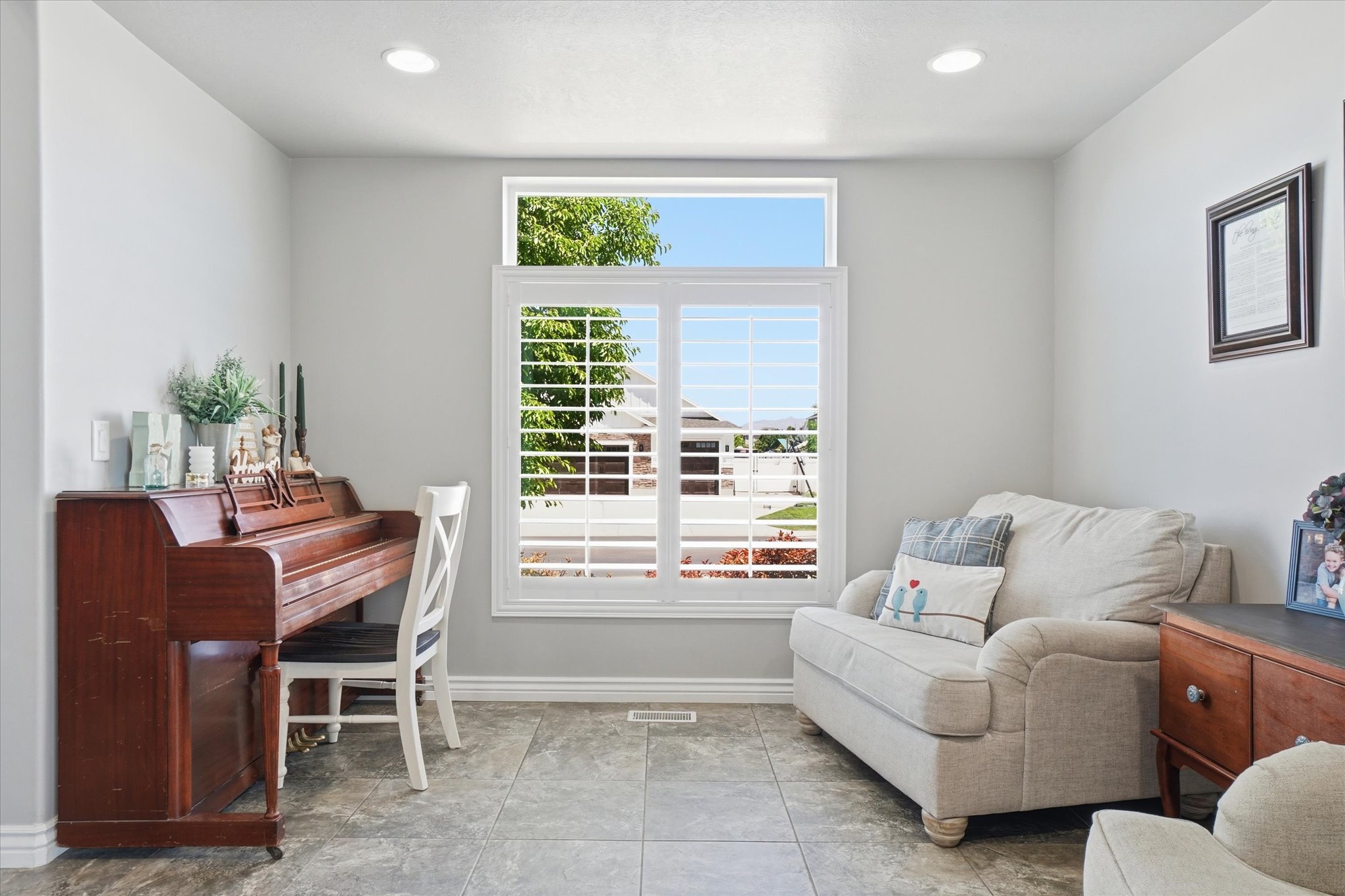 Generous window with white louvered shutters and upper transom, recessed ceiling lighting, light gray wall paint, and gray tile flooring