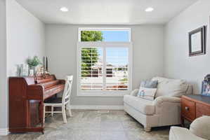 Generous window with white louvered shutters and upper transom, recessed ceiling lighting, light gray wall paint, and gray tile flooring