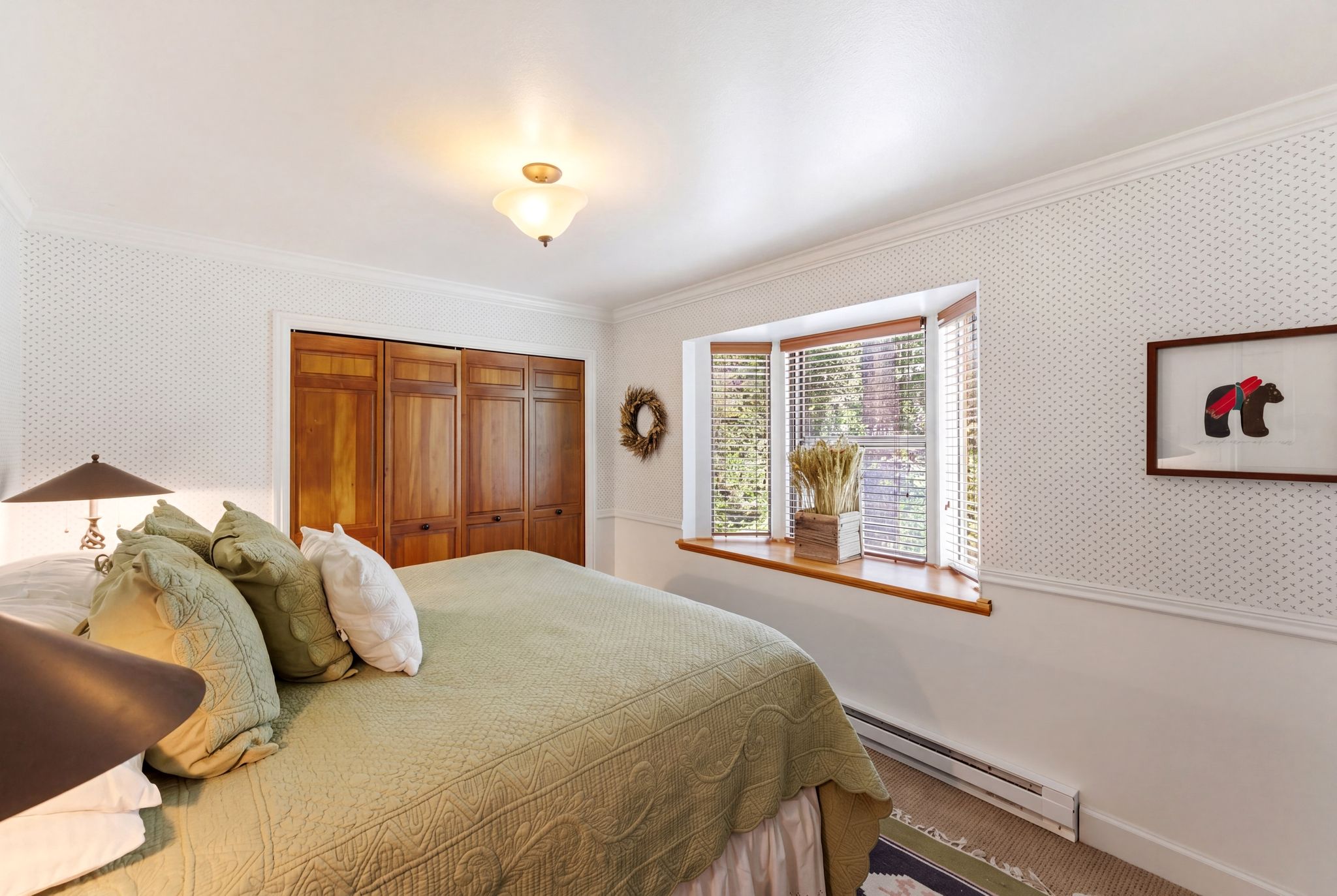 Bedroom featuring a bay window with wood blinds, wood-paneled closet doors, and crown molding