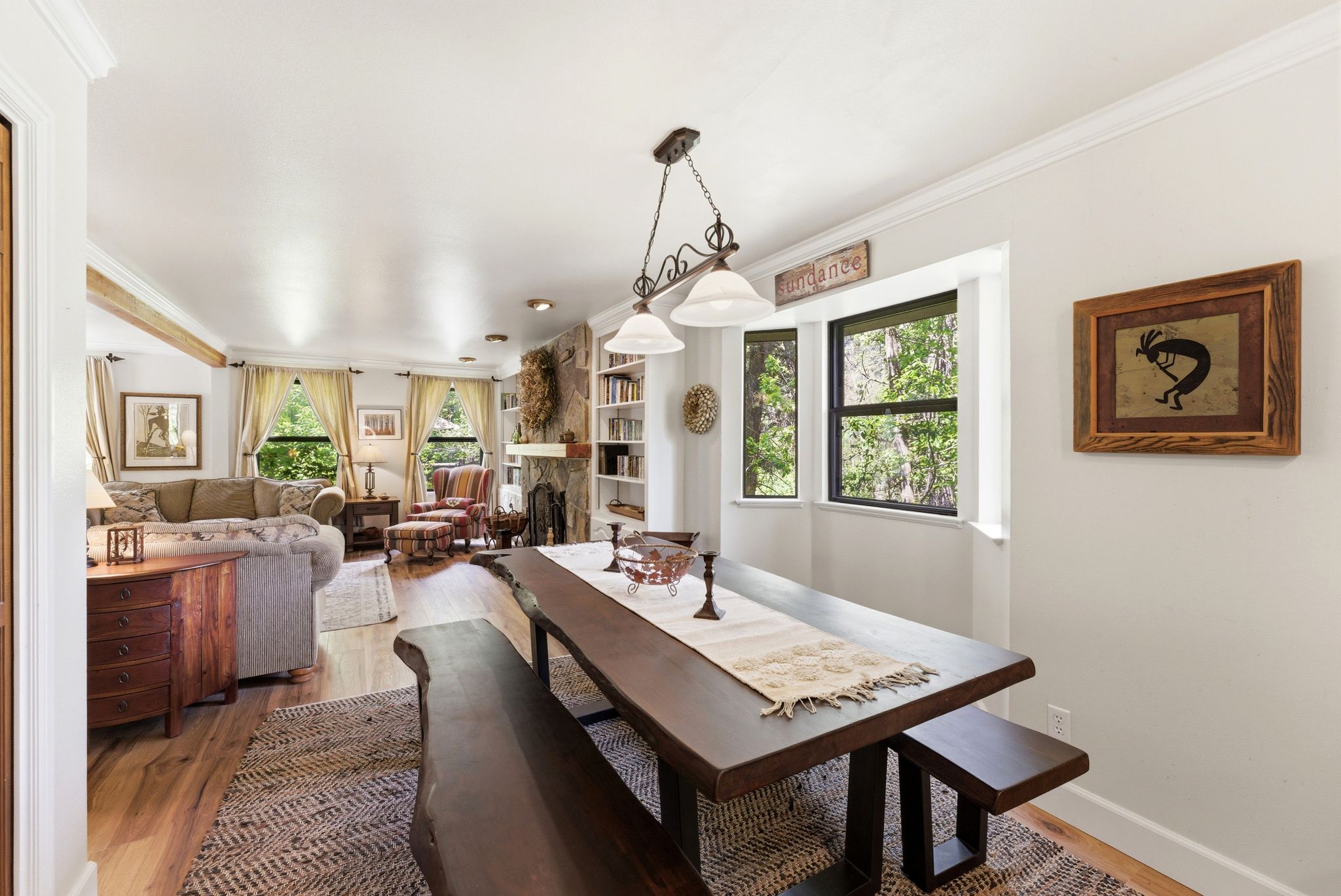 Dining area featuring a wood-finish table with matching benches, a decorative area rug, and a bay window