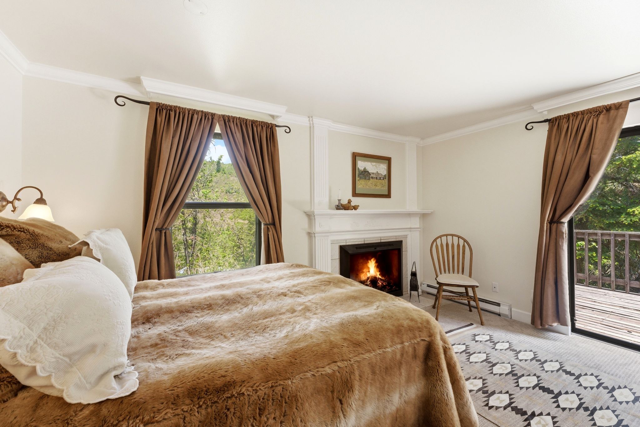 Bedroom featuring a fireplace with a white mantel, crown molding, and light-colored walls