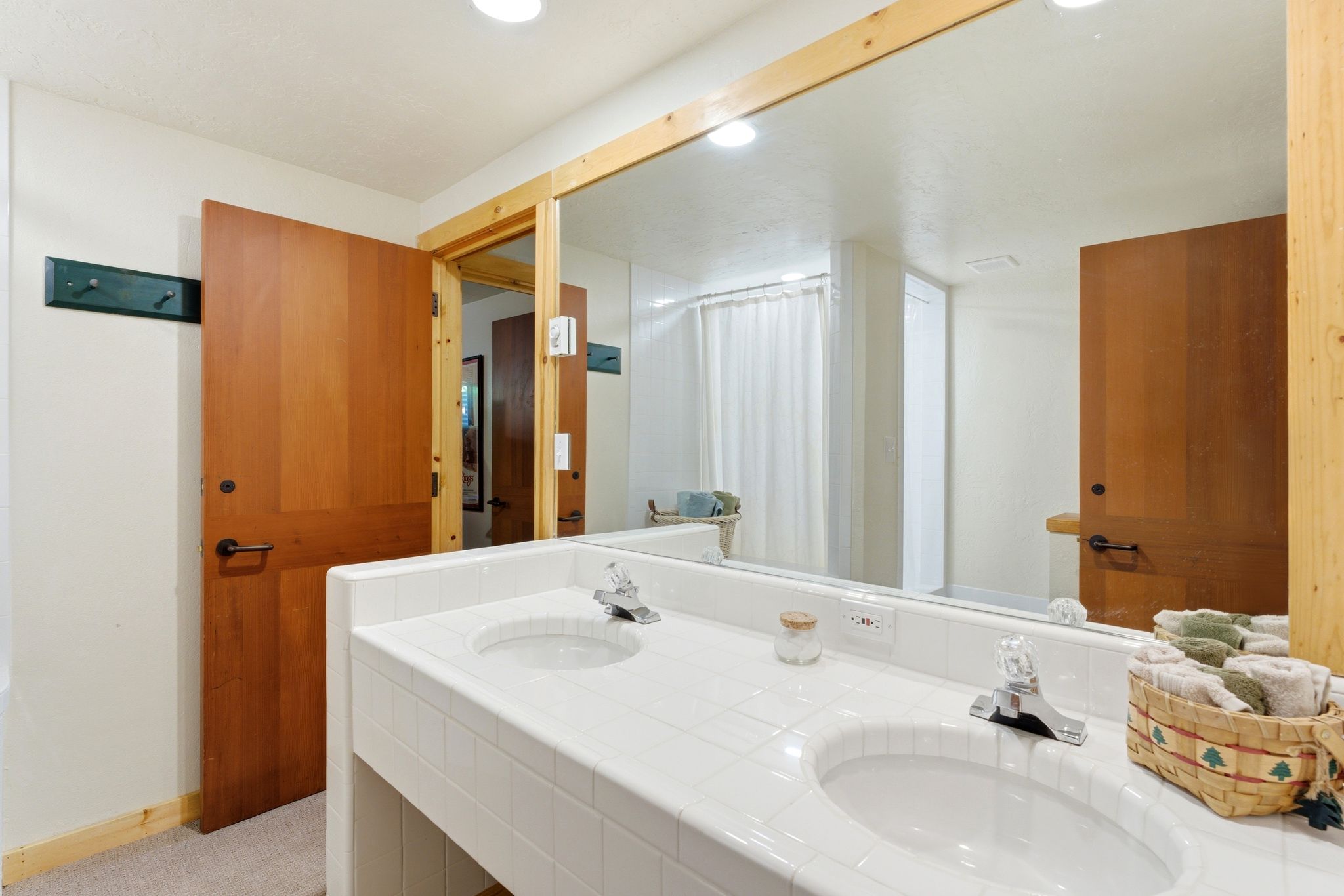Double vanity featuring two integrated sinks with chrome faucets, a tile countertop, and a large wall-mounted mirror