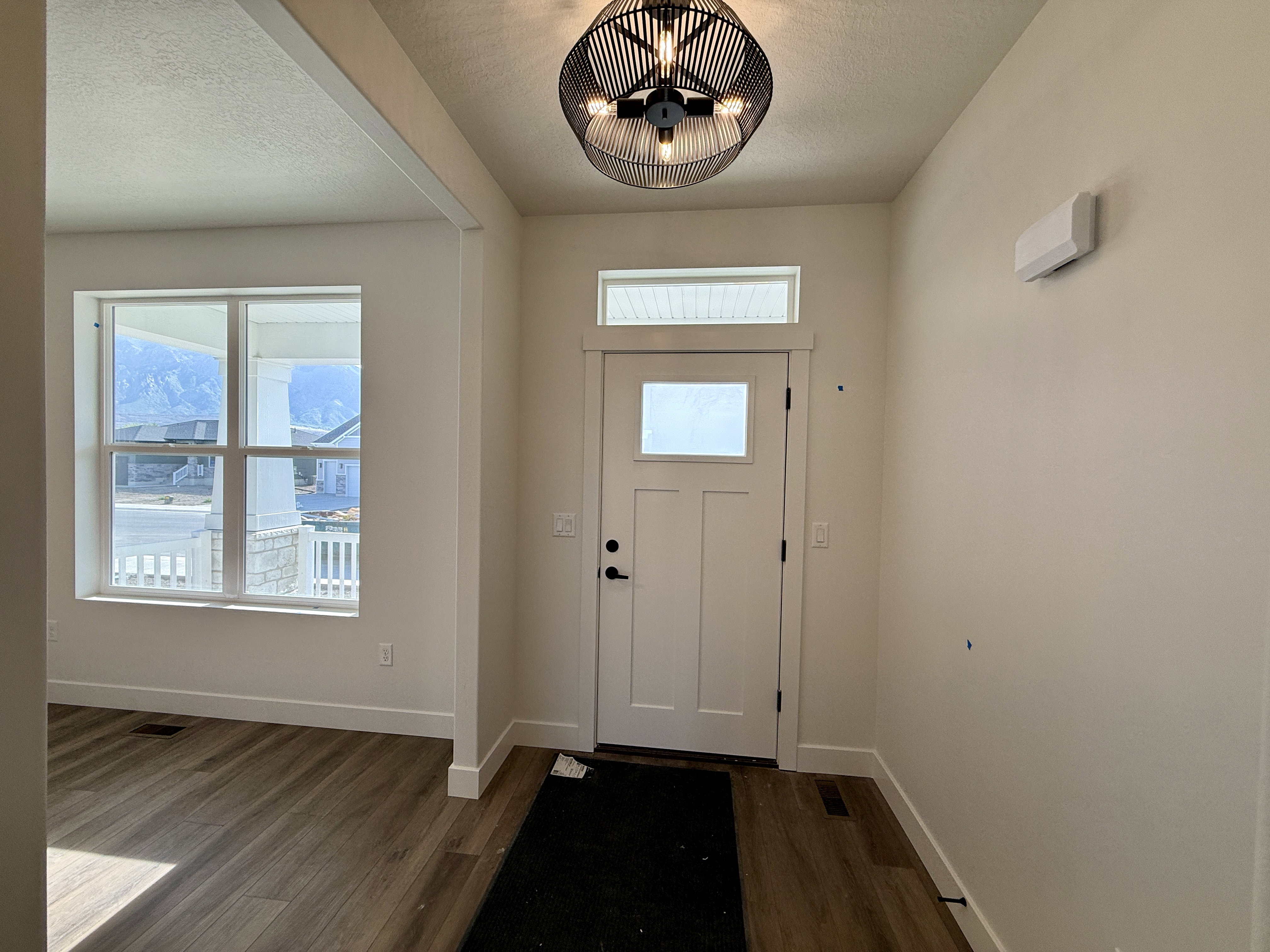 Entryway featuring a paneled door with frosted glass, transom window, and a contemporary black geometric chandelier