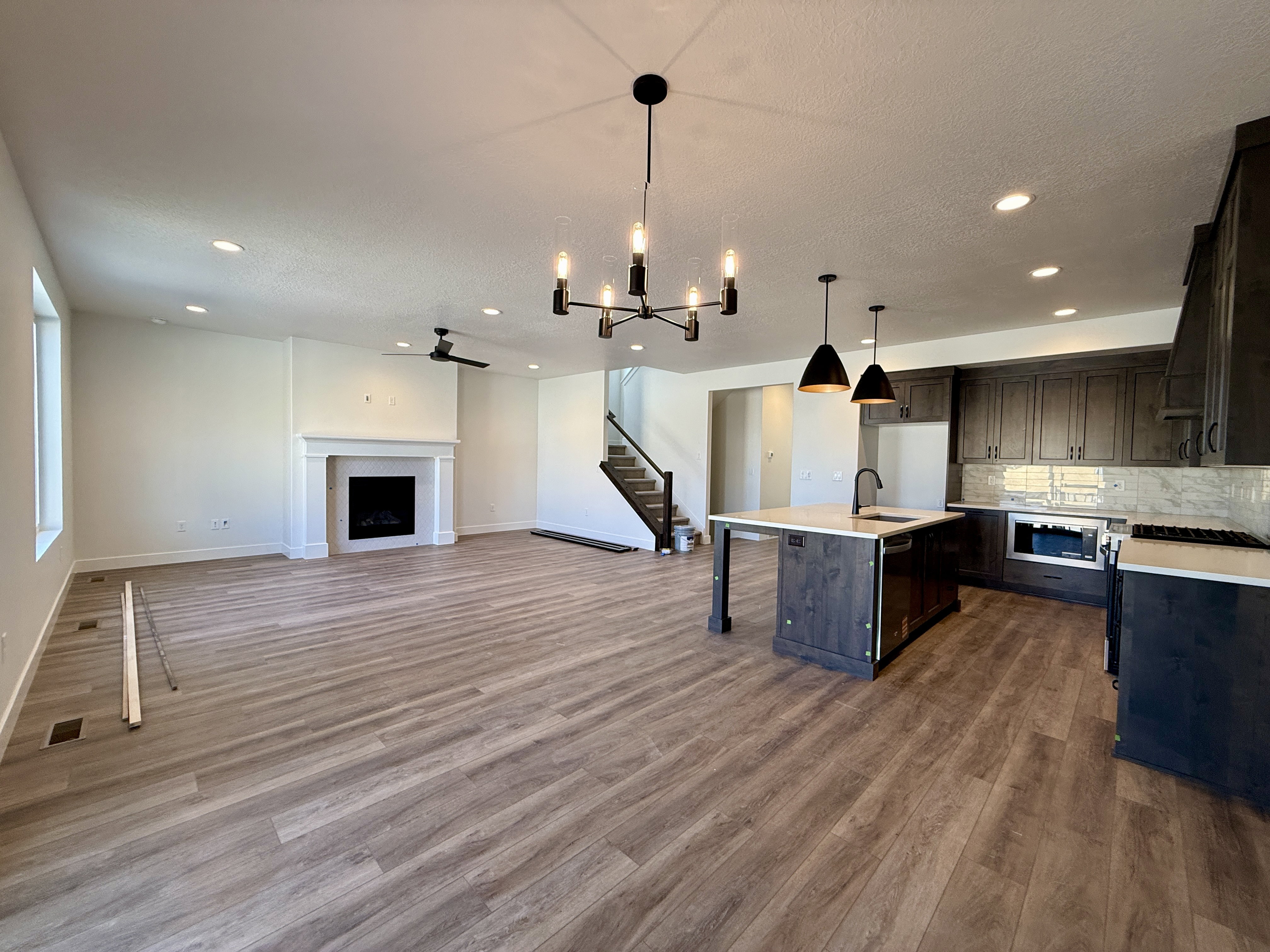 Open-concept living space featuring wood-finish flooring, a white-mantled fireplace, and recessed lighting