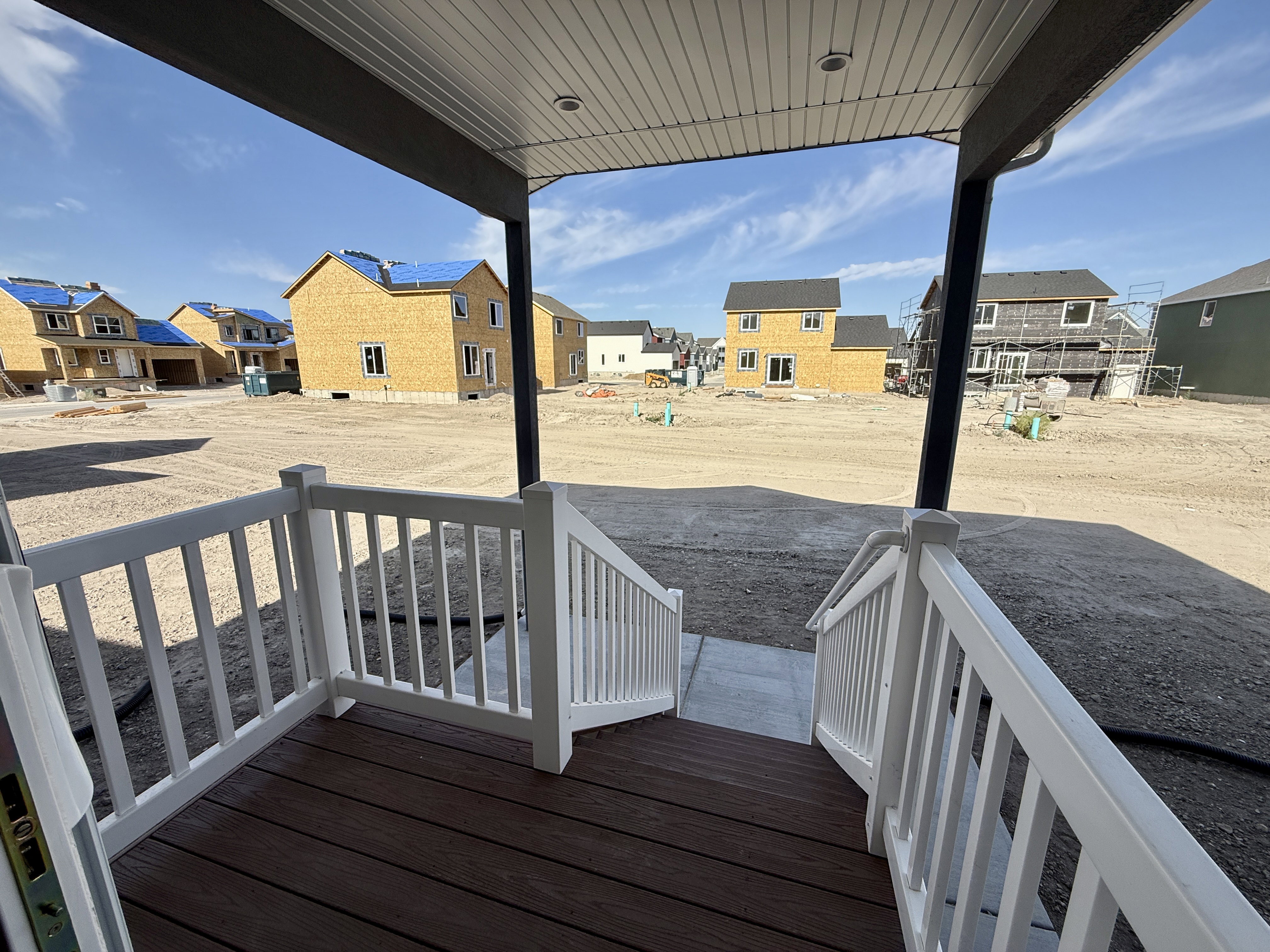 Inviting front porch featuring rich wood-finish decking and crisp white railings