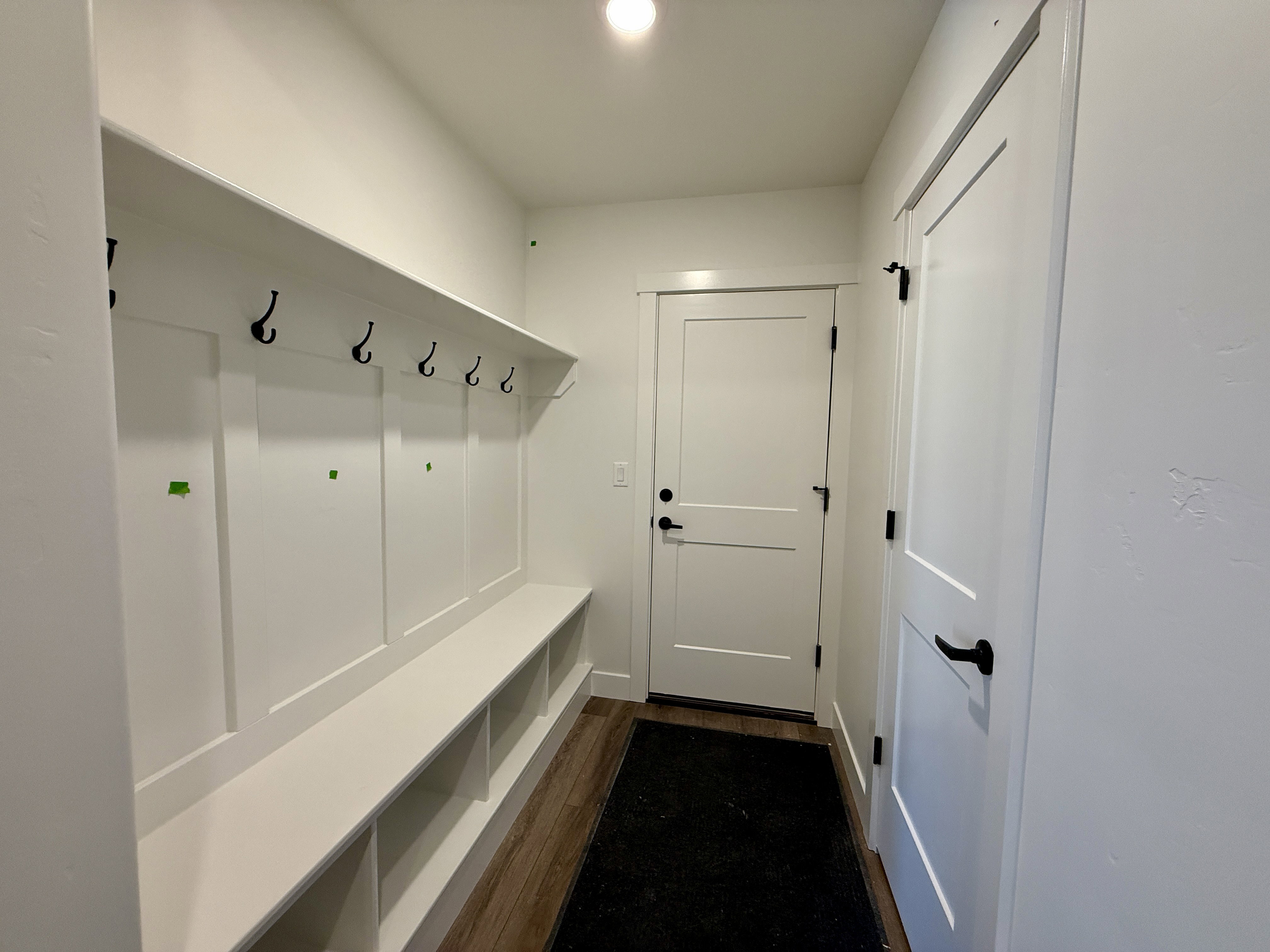 Entryway featuring built-in white bench storage and coat rack with black hooks