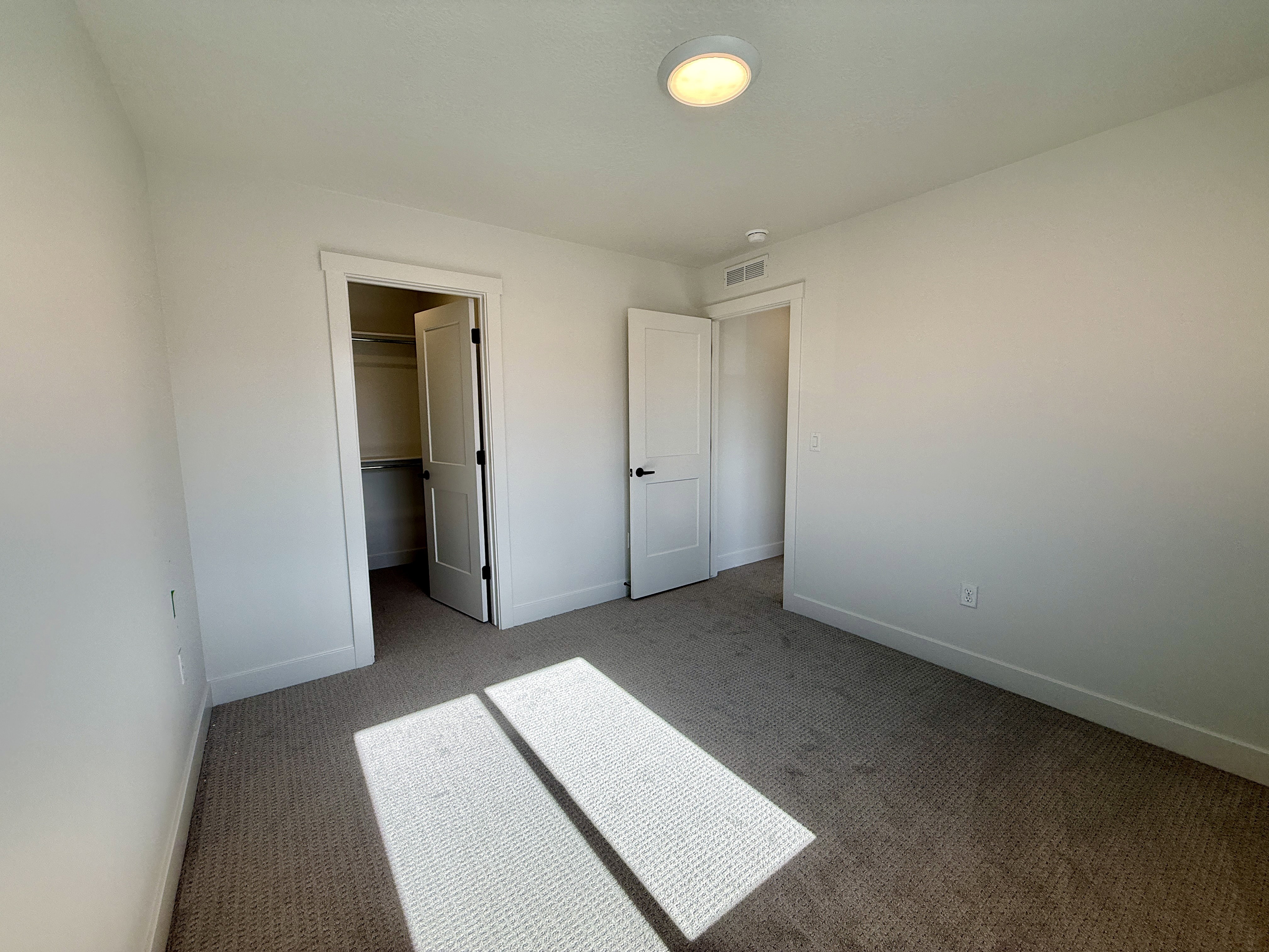 Carpeted room featuring white walls, a flush-mount ceiling light, white trim, and a closet with bifold doors
