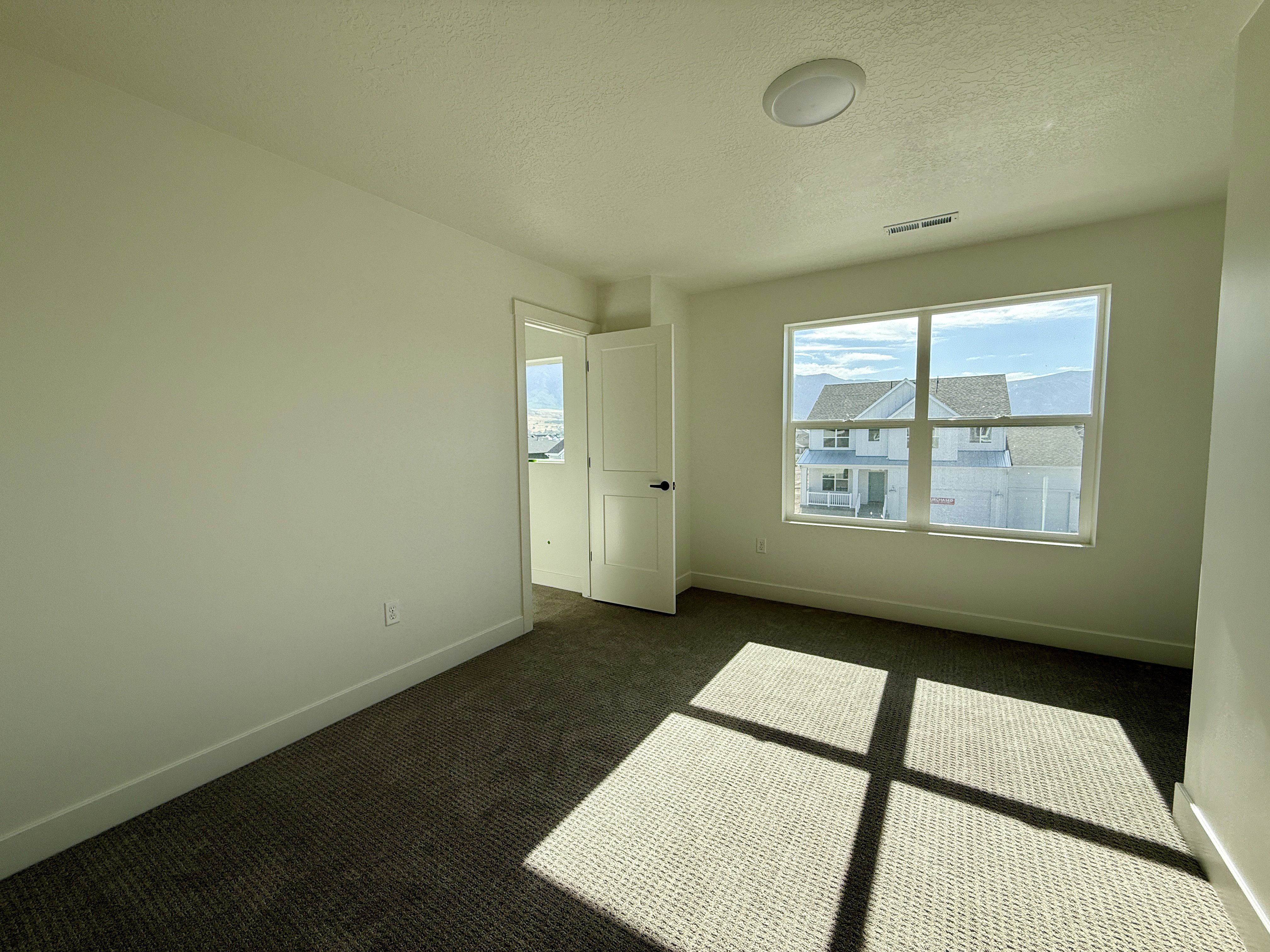 Room featuring a large window, neutral carpeting, light-toned walls, a flush-mount ceiling light, and white trim