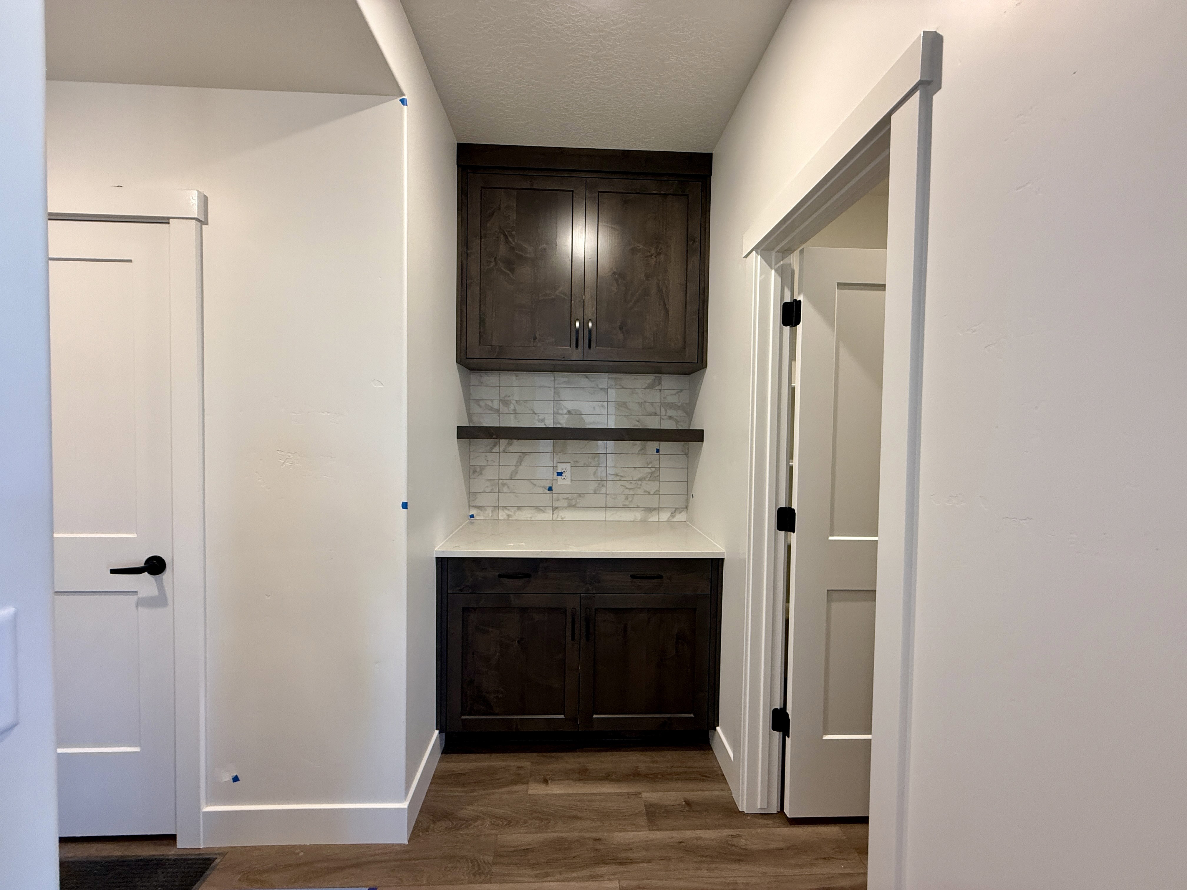 Built-in cabinetry with dark wood-finish doors, a light-toned countertop, and a tiled backsplash