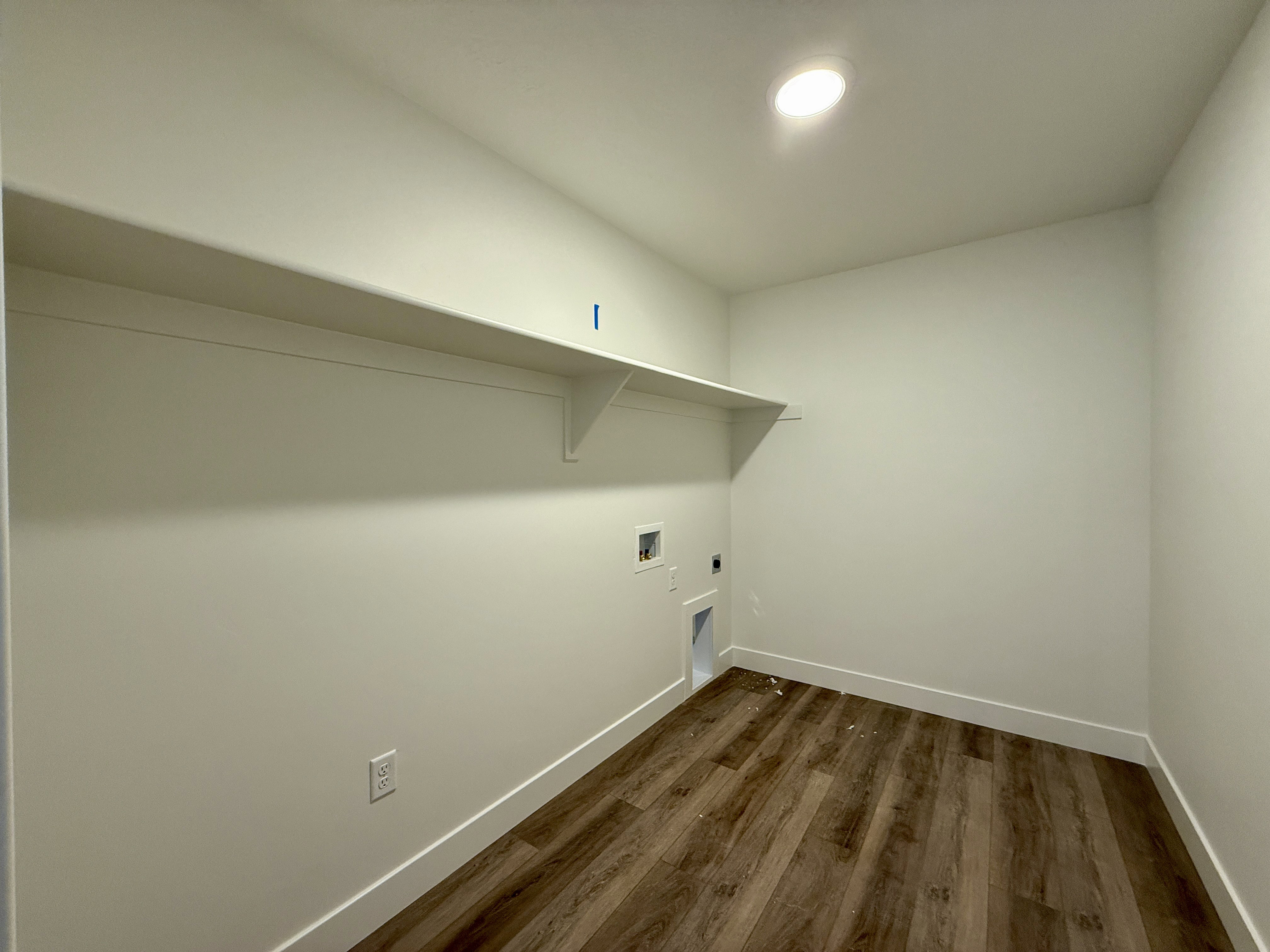 Laundry room featuring wood-finish flooring, white baseboards, a built-in shelf, and recessed lighting