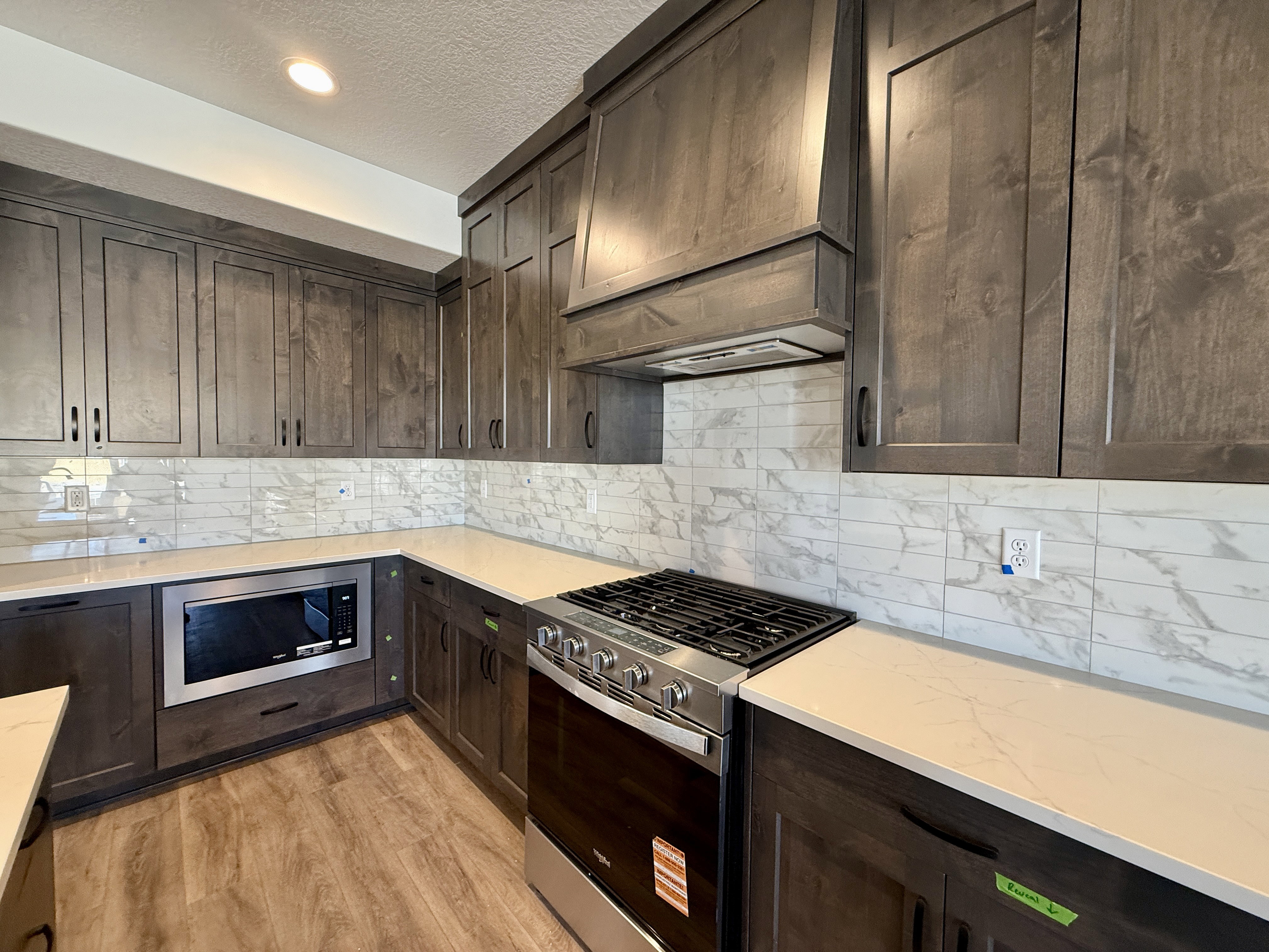 Kitchen featuring wood-finish flooring, dark wood cabinetry, white countertops, and a white subway tile backsplash