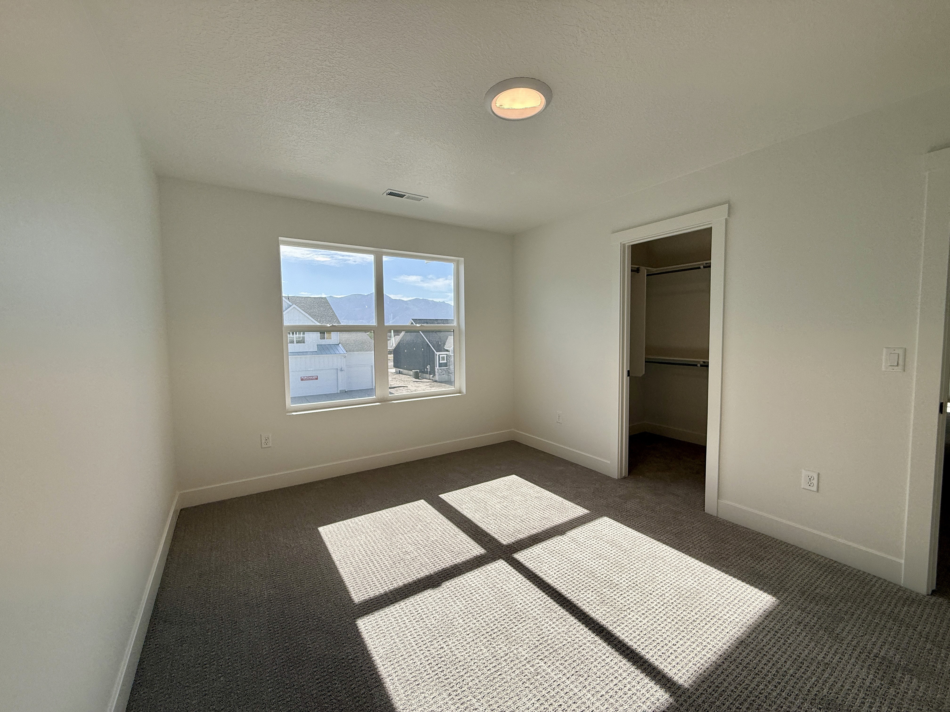Carpeted room featuring a double window, recessed ceiling light, and a built-in closet with shelving and hanging rods